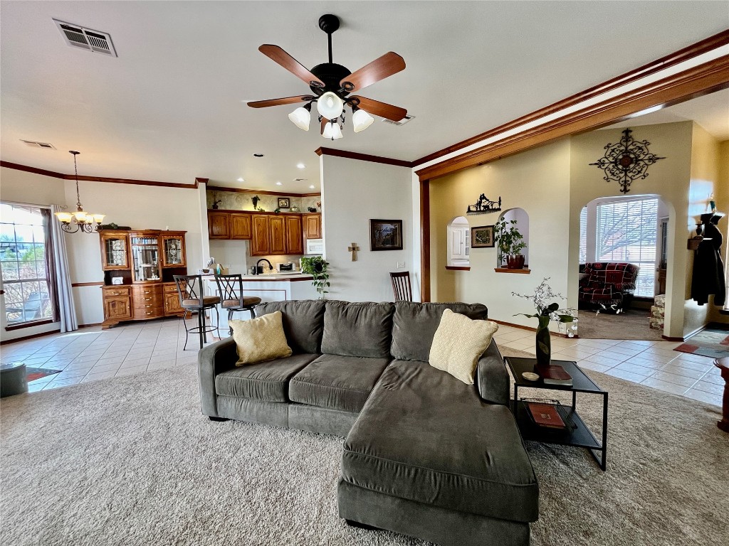 5808 E McMillin Dr, Tuttle, OK 73089 living room with light tile flooring, sink, ornamental molding, and ceiling fan with notable chandelier