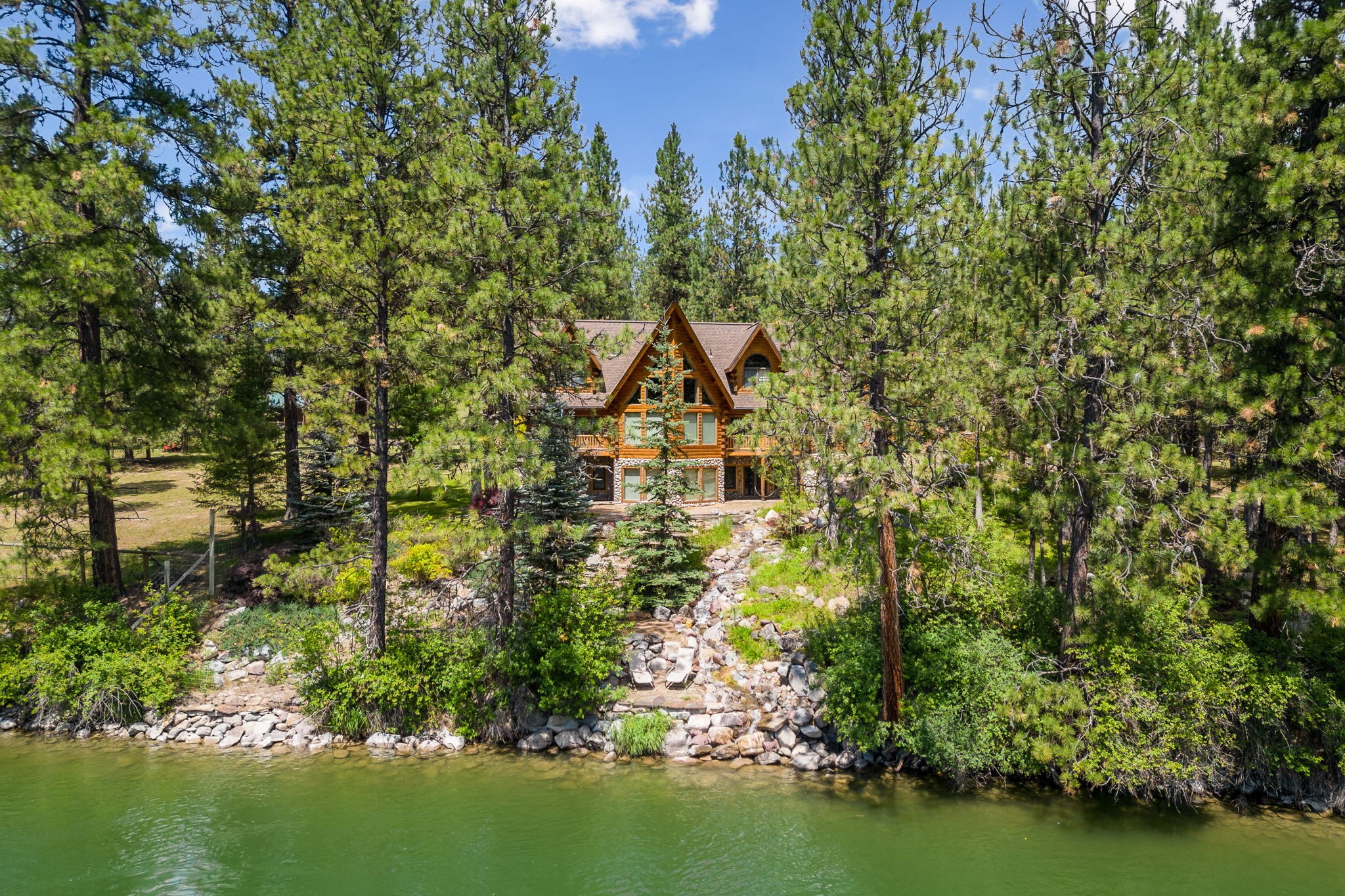 Imagine a majestic log home that truly encapsulates the heritage and spirit of Montana – tall pine trees, breathtaking mountain views, and the slow-rolling Clark Fork River. If you’ve been searching for the perfect Montana property, we’d like to welcome you to 64 Steamboat Way - on 3.45 acres and almost 400 feet of river frontage - in the quiet and picturesque town of Thompson Falls, Montana. 

Featured in Log Homes Illustrated for its custom grandeur, this show-stopper sits on the banks of the Clark Fork River. Nearly every window provides a tranquil river view in this 6400-square-foot D-Style mountain log sanctuary. The heart of the home is adorned with a floor-to-ceiling river-rock fireplace and a large, family, eat-in kitchen accented with an antique stove.  The main floor is enclosed with white pine logs, and the interior doors are Amish made – extra wide and 2” thick. Vaulted ceilings and cozy lofts throughout offer open, breathtaking views and quiet places to watch the river – and all the birds and fish that call the river “Home.”

The main floor features a warm and inviting owners’ suite, with river views that make it seem like a vacation resort. The generous owners’ bath boasts a steam shower. Upstairs, two welcoming guest rooms bookend a spacious and relaxing loft area that overlooks the meandering Clark Fork and the whispering pines.

One of the home’s most unique surprises is “the doghouse” – the original owner’s name for the approximately 40x26 foot Bonus Room, complete with bathroom and kitchenette. This area makes an exceptional getaway for guests, a hobby room, or space for adult kids, extended-stay guests, or other family members.

Speaking of exceptional getaways, they are in abundant supply at 64 Steamboat Way. You can choose to luxuriate in the property’s Butchart Garden-like landscape, the log gazebo on the river, the hot tub, or on the river bank.  The quaint little guest cabin has a Jeremiah Johnson vibe to it – you can almost hear and see all of civilization disappear when you walk through the door. Wherever you decide to relax on this property, you’ll be surrounded by the serene peace only found in a true Montana setting like this one.
