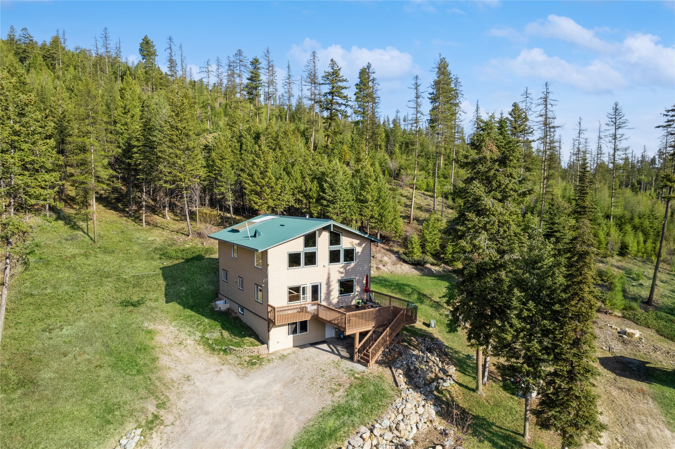 MOTIVATED SELLER for this home with end of the road privacy with over 13 acres of forest and meadows- adjacent to Stoltze Land & Lumber property.  3 bedrooms and 3 bathrooms on multiple levels provide an expansive interior of over 3000 square feet with bonus rooms throughout.  Upper level has bedroom, bath and loft with mountain views.  Main level consists of generously sized 2 bedrooms, bath, living, dining and kitchen as well as spacious deck.  Lower level has accommodating family/multi purpose room, bonus room with plenty of light and a bathroom.  Eastern portion of property is relatively level with grass area.  Forest proceeds up the hillside to the west.  Ample room for additional structures.  Convenient location approximately 5 miles from Farm to Market Road.  Easy access to Kalispell.