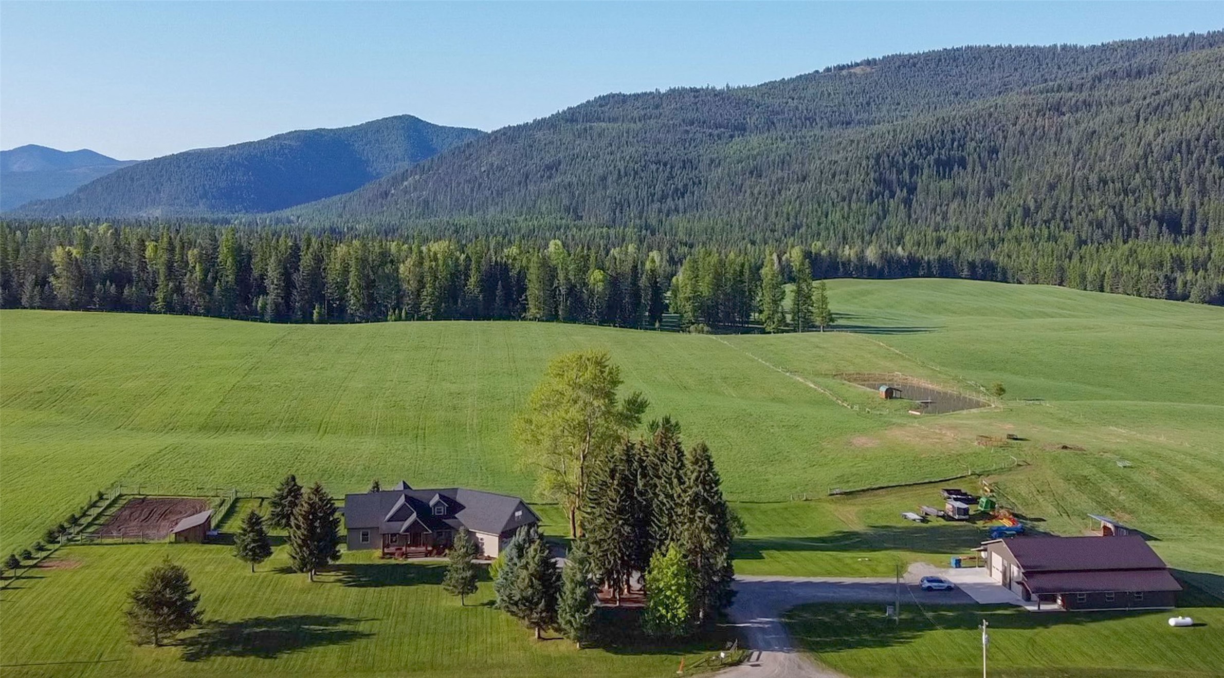 Experience all the best of Montana on 30+- acres of fenced hay ground with a pond, custom, craftsman home of 4576 sq. ft., 7 bedroom, 5 baths and a 40x60 shop with additional 12' enclosed bays. 

Custom beam work greets you on the covered front porch, entering into a generous foyer with large coat closet and beautiful circle sawn fir flooring.  Gorgeous, wide rustic alder trim and doors accentuate the open floor plan.  Custom fantastic antiqued rustic alder cabinets are aesthetic & work wise with a Costco/Trader Joe pantry near. Loads of formica counter space with Gemloc edging, including ample seating, are ready for your amazing kitchen creations.  Main floor master suite with walk-in closet and soaking tub with a view.  

The panoramic mountain views are indescribable.  Whitepine Creek is known for unending recreational possibilities, with huckleberries, hunting, biking, hiking, horseback riding and access to millions of miles of National Forest.  Too much to list!  Welcome home. Barn wood wainscoting accentuates the 40'x60' shop with 14' side walls and enclosed 12' shed-roofed rooms.  A sizable office toward the county road has a built-in granite-topped desk, 1/2 bath and incredible views for you telecommuters. In-floor heat is a great touch.  12'x12' garage doors should accommodate whatever toys you want!  White metal finish on the interior of the main portion of the building make it light, bright and clean.  

The west wing of the home houses three bedrooms, a sitting room and a double-sinked full bath.  The lower level has a master suite with 3/4 bath, 2 additional bedrooms, a bonus room, utility room, w/d hook-ups, a large full bath, and wood stove-heated recreation room.  Laundry available on main and lower floors, with laundry chute in upstairs bath.  Once in the oversized two-car garage, you enter into the utility/laundry room to the right or the pantry and kitchen down the hall to the left.  Powder room on the main, along with a deck overlooking the fields.  A propane furnace with heat pump and A/C, as well as wood heat warm the home, and the spray foam and fiberglass information creates an efficient and easy to heat home (R-23 walls and R-50 ceiling).  

The fenced garden area overflows with produce from many years of production in its soil, along with apple trees.  A wood shed full of split and stacked wood for next year isn't far from the outside accessed woodbox next to the wood stove in the basement.  Old growth trees surround the house and an underground sprinkler system makes maintaining lush three-acre lawn a breeze. 21 acres of the land are in hay field, while 6 acres contain a fenced pasture.  All of this is possible from a 281' deep, 30 gallon per minute well with a continuous pressure pump installed in 2021.  The pond is fenced with a dock and shed with views up Whitepine Creek.

Bring your fishing pole and dreams.  You won't have to do anything to this one.  It is move-in ready!