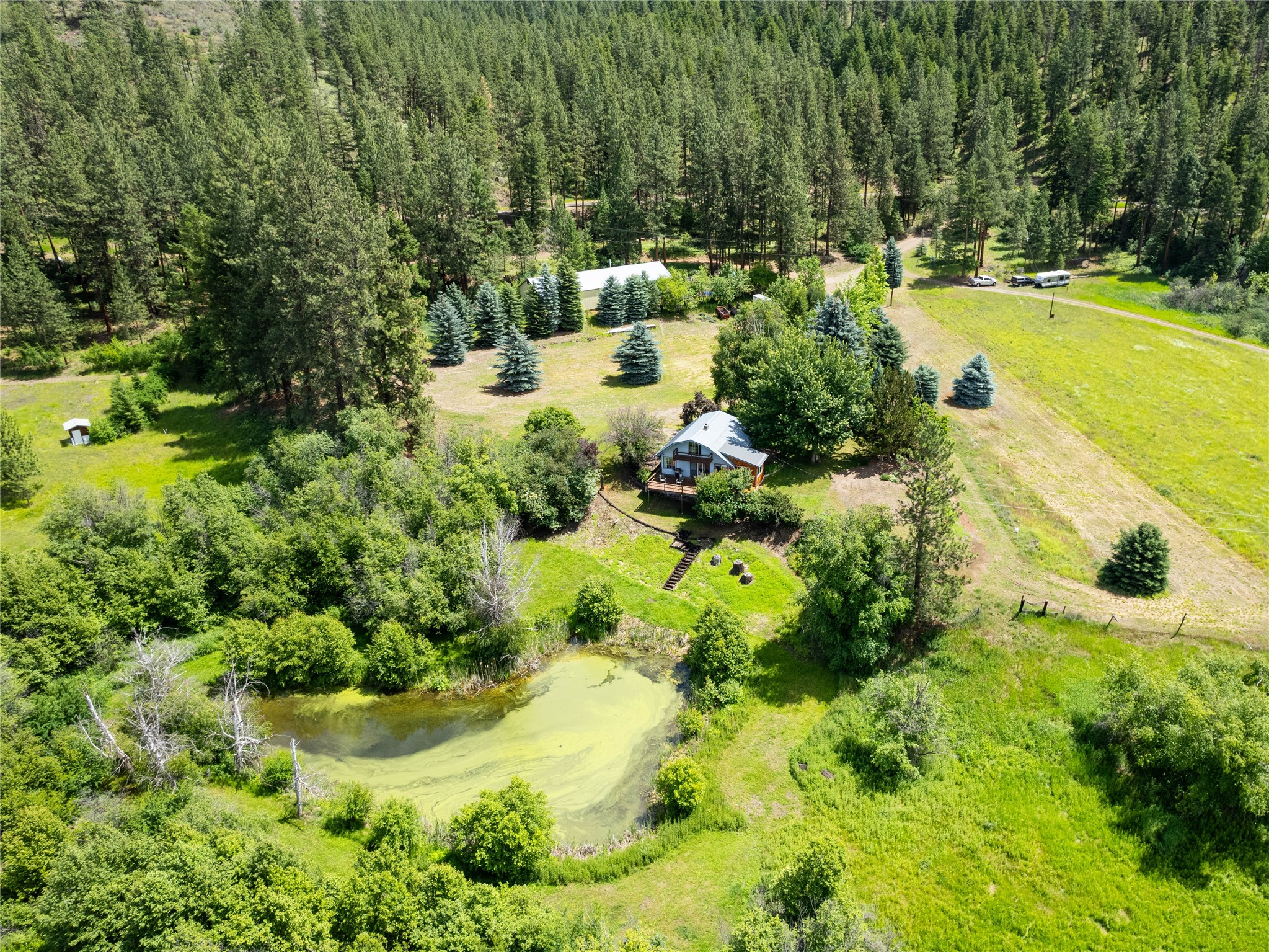 These captivating 22+ acre parcels offer a harmonious blend of natural beauty and the comforts of home. Situated in a picturesque location in Northwestern Montana, this property boasts a diverse landscape with forested areas, tillable meadows, two charming homes, multiple additional build sites and a large 30x90 ft. insulated and plumbed shop. The property abuts 560 acres of State Land that leads to 164,000+ acres of USFS! 
Adjacent to the parcels, an additional 30+ acres are available for lease coupled with a separate long-term purchase contract, providing an exceptional opportunity to create a larger estate.

As you explore the property, you'll be enchanted by the lush, marketable forested areas. Towering trees create a serene atmosphere, providing privacy and inviting you to wander along peaceful trails. Intermingled with the wooded sections open cultivatable meadows, pre-plumbed for irrigation, where sunlight cascades down onto the vibrant green grass. (See Supplemental Remarks) These expansive meadows present endless possibilities for outdoor activities, growing crops, pasture land, gardening, farming, raising animals or simply enjoying the panoramic views of the landscape.

Adding to the allure are two homes, totalling 3,033 square feet and 4 bedrooms and 3 bathrooms, each offering their own unique charm and functionality. The first exudes a cozy ambiance, with its comfortable living spaces, spiral staircase, and large windows, this home provides a perfect retreat for relaxation and tranquility. The second home is the perfect guest, extended family or income producing property. 

The contiguous 30-acre parcel seamlessly blends with the existing properties, sharing the same captivating natural features of forested and meadow lands, providing endless opportunities to develop into your own private estate or potentially subdivide, taking advantage of numerous building spots.

Whether you aspire to expand your living space, indulge in ambitious development projects, or simply relish the freedom and privacy of a larger estate, the option to purchase an additional 30 acres adjoining the original 22-acre parcel presents an extraordinary chance to shape your own idyllic sanctuary in perfect harmony with nature.