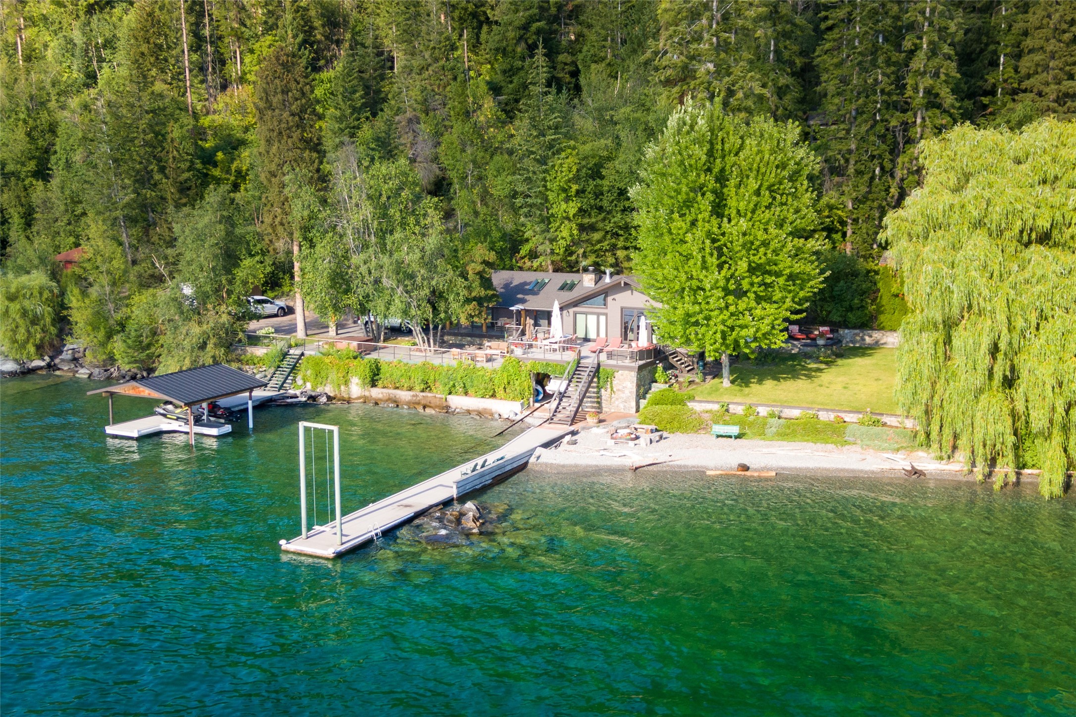 Imagine living with Flathead Lake just outside your front door! This 4 bedroom 3 bath turn-key, fully furnished home is sited to perfection on 1.5 acres with 241 feet of prime frontage. The 2 docks with Jet Skis and indoor boat storage with boat are ready for you to come and enjoy the summer! The flowing indoor/outdoor living space is an entertainer's dream and the hot tub and beach front fire pit beckon family and friends for endless conversations and memories created. Grandfathered boathouse and home on the lakefront. It doesn't get any closer. Spectacular Flathead Lake Waterfront Investment. Contact Amy Bain-Wilson at 406-370-9101, or your real estate professional today for details and a showing.