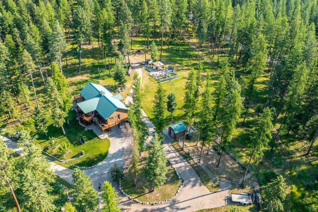 Escape to a recreational paradise on 31 subdividable acres bordering the Forest Service. This lodge-style home offers rustic charm and modern updates, including custom cabinets, quartz countertops, and newer appliances. The great room features wood-beamed ceilings and a stone fireplace, while the master suite boasts vaulted ceilings and a jacuzzi tub. Enjoy mountain views from giant picture windows or the wrap-around deck. Outdoor living includes patios, a gazebo, and fire pit. A 60x48 shop with radiant heat could be converted to living space or equine facilities. Explore groomed trails connecting to thousands of acres of Forest Service and State land for hiking, biking, horseback, skiing, snowshoeing, and hunting. Lush landscaping, vegetable garden, fruit trees, and wild raspberries enhance the nature lover’s oasis. The aquifer well provides perfect unfiltered drinking water. Located between Kalispell and Whitefish and convenient to ski resorts, Glacier Park, and Flathead Lake.