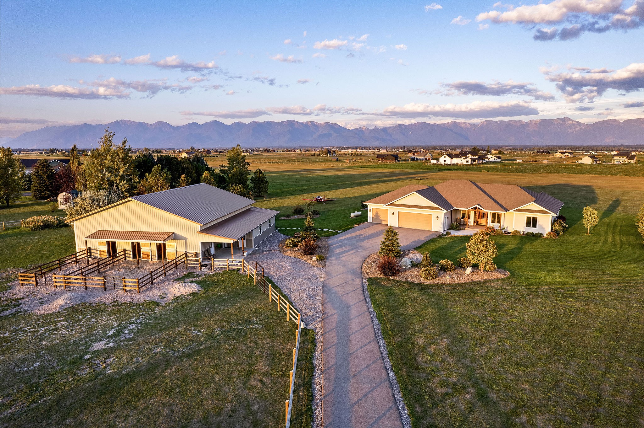 Rare and refined, custom built ranch home located in Lower Valley with incredible 360 degree views! Situated on 10 level acres between Sky Ranch's private airstrip and the protected Blasdel Waterfowl Production Area, this exceptional property is an aviator’s dream with a custom hangar and direct access to the runway. Additionally, this meticulously maintained ranch property offers an equestrian lifestyle with a beautiful 3-stall barn, paddocks, fenced pastures and amenities. The single level, 3 bed, 3 bath residence exudes quality and fine craftsmanship befitting the well thought out design that brings views in from every direction. Discerning buyers will appreciate the open floor plan, large master suite, second guest suite and top-notch finishes including hickory floors, custom built alder cabinetry and alder doors & trim. If you are looking for a versatile property that has fly in, fly out potential and panoramic views, this is it! Enter this property on a quarter mile fence-lined driveway and you’re greeted with a home built to take in the views.  Soaring ceilings and large windows feature spectacular, open views of the Swan and Mission mountain ranges to the East and Blacktail and the Cabinet Mountains to the West.  From Glacier National Park to Flathead Lake, sunrise to sunset, this home was built to take in the views!

In an elegant, neutral palette, the open floor plan of the home features Hickory flooring and a beautiful natural stone fireplace in the living room with custom mantle. The cabinetry and trim are all custom built in Alder with soft-close drawers. The kitchen is appointed with stainless steel appliances and large, curved island and opens to the dining area as well as the screened-in patio for seamless indoor and outdoor entertaining.

The primary bedroom features beautiful views, large windows and sitting area, as well as a walk in closet with built-ins.  The spa-like bath features abundant cabinetry, modern glass shower and soaking tub.  The large secondary bedrooms also have beautiful views, and one features an ensuite bath with walk-in closet.  This thoughtfully and stylishly designed home also features a home office with French doors, laundry room with plenty of cabinetry and countertops and a bonus room that can be used as a hobby room, art studio, or home gym. 

The lighted and thoughtfully finished garage is oversized with built-in storage cabinets and hot/cold water.  The third garage bay is finished and heated and is ideal for a shop or woodworking.

The unique and custom-built hangar features a 40-foot bi-fold door, LED lighting and large concrete ramp with tie-downs which opens up toward the Sky Ranch runway. Although shared in the same 3000 sq. ft. building, the hangar is entirely separate from the beautiful 3-stall barn and paddocks.  The barn features a covered patio with separate entry, hay and feed storage, custom stall hardware by Noble Equestrian, tongue and groove finishes, tack room and roll-up garage doors for easy access, feed delivery, or trailer storage.  

Frost-free water hydrants on both sides of the barn, and in the interior provide year-round ease of maintenance for animals.  Thoughtful planning and high-quality construction define barn, paddocks, and approximately 6 acres of fenced pastures with loafing shed, gates and easy access in and out for trucks, trailers and farm equipment without having to use the paved driveway.

The incredibly maintained, professionally landscaped yard features plants that alternately bloom all season long and extensive use of crushed rock, river rock and flagstone.  The fenced garden is an organic gardener’s haven and provides the ultimate in farm-to-table lifestyle.

This is a rare and unique opportunity for the most discerning buyer looking for a fly-in ranch property with exceptional views.