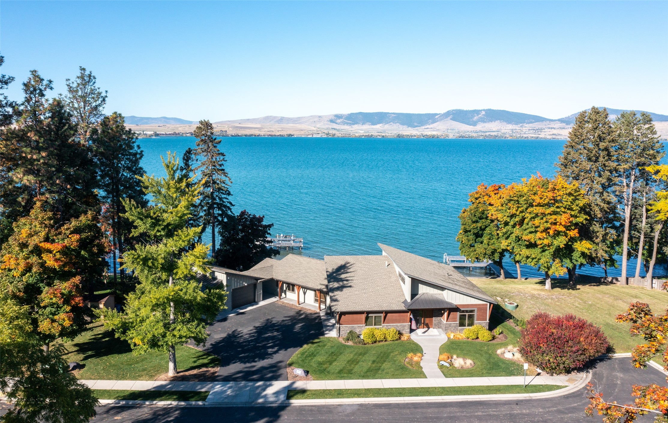Welcome to 103 Anderson Place, on the shores of Flathead Lake! This thoughtfully designed residence, built by the esteemed Gallatin Construction in 2016, offers a lifestyle of comfort, convenience, and natural beauty.  Located just a chip shot from the 3rd Tee box of the 27-hole Polson Bay golf course, this inviting home calls you to live life to the fullest.  The 3 bedrooms, 2 1/2 bathrooms, 2708 sq. ft,  predominantly one-level floor plan with zero-entry, is perfect for all generations.  Every evening, embrace the breathtaking beauty of Montana's sunsets as they paint the sky over Flathead Lake. Huge windows frame these colorful vistas, creating a living canvas in your very own home. The patio is your private sanctuary, featuring a propane fireplace overlooking your 126’ of frontage, complete with a 120' long dock with a boat slip. Whether you're gathering with friends or simply enjoying a quiet evening, this space is perfect for entertaining and relaxation.  Soak in the soothing waters of your own Hot Spring Spa with a stunning view, the ideal way to unwind and rejuvenate amidst the serene surroundings.  Your primary suite is complete with patio access, heated bathroom floors, a separate shower, a deep soaking tub, and a walk-in closet. Start your day with a round of golf amidst picturesque Mission Mountain and lake views. In the afternoon, surf or sail on the crystal-clear waters of Flathead Lake.  103 Anderson Place is more than a home; it's a gateway to the best of Montana living. Whether you're seeking serene relaxation or outdoor adventures, this lakeside gem has it all.  Your Montana dream begins here. Please see feature sheet for more details.  Agent owned.  Call Amy Peterson at 406-370-7071 or your real estate professional.