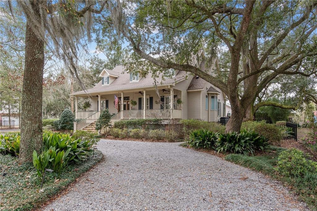 Custom Acadian surrounded by huge Live Oaks with expansive sitting porch one block from the Lake in Old Mandeville. Soaring cathedral celings with exposed beams, open airy floor plan overlooking glorious grounds. Hardwood floors, updated kitchen with granite counters and breakfast bar. Butlers pantry with additional storage, wood shelving and wine cooler. Two bedrooms down, two bedrooms up. Primary bedroom suite w floor to ceiling windows, opens to back deck. Garage attic potential living space.