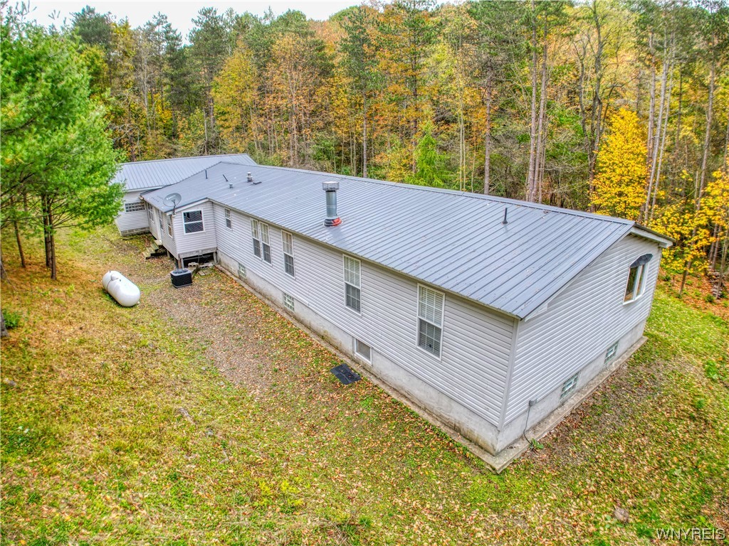 Secluded wooded setting with 10+ acres, offers enjoyment all four seasons in the rolling hills of Cattaraugus. Only minutes to everything Ellicottville, Including both ski resorts, shopping, dining & more. The large home has two suites (Primary & Secondary), a bunkroom w/ 2 bunk beds, plus a fourth bedroom and additional full bath. Open concept throughout the kitchen, dining, living area w/ WBFP (Propane & Wood) and glass block, custom bar w/ granite top & bar fridge. Space for the entire family to gather after their outdoor activities, plenty of acreage for adding walking/riding trails. The heated two car garage (32x23) has extra space for your snowmobiles, ATVs, and other outdoor gear! A covered walkway connects the garage and home for extra storage and protected access during the cold winter months, leading you into the mudroom/laundry room for easy entrance and clean up! The back deck offers you a seating area and grill to enjoy the views. This home also has central air for relaxing in the hot months. Sleeps up to 12 people, not including couches, perfect for short term rentals. In a prime location, offering lots of privacy, this home won’t last long!