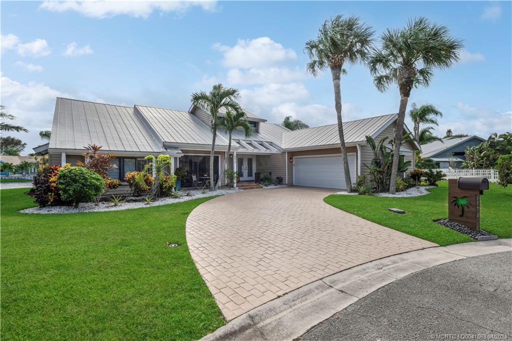 Welcome to your dream home! This move-in ready 3-bed, 2-bath gem offers everything you've been searching for and more. Living room has wall of sliding glass door that access the large deck and take in the breathtaking lake views. Relax in the hot tub and enjoy the lake views. With fully paid solar panels and 3 Tesla batteries, rest assured that you'll have electricity even during power outages, providing peace of mind and sustainable living. The home has new kitchen and baths. Tile flooring throughout, impact glass windows provide, safety & energy efficiency, and Plantation Shutters throughout. Oversized 2 car garage for room for cars and toys! New rip-rap seawall to protect from erosion. Don't miss this incredible opportunity to own a home in a great neighborhood that combines stunning views, eco-friendly features, and stylish upgrades. Approximately 1 mile to Hobe Sound public beach.  8 miles to I-95.  Plenty of local shopping and restaurants.