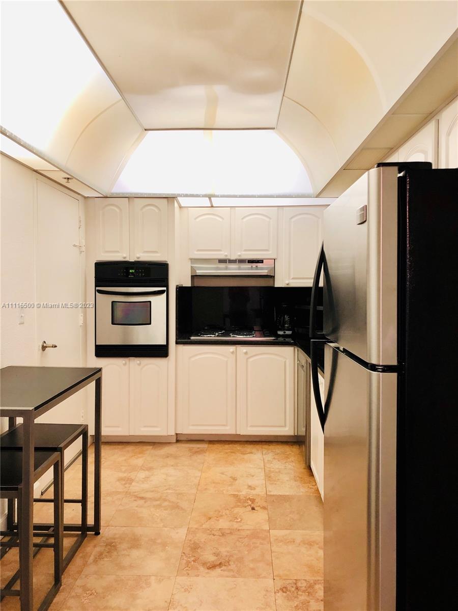 White Kitchen Cabinets with Stainless Steel Appliances and an Eat-in Area