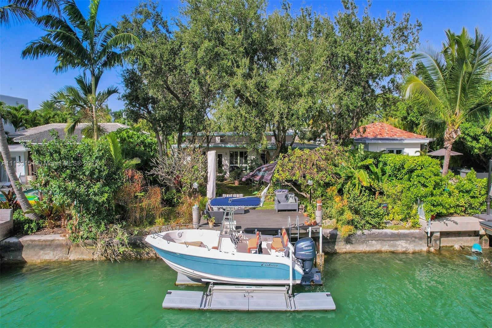 Step into an urban jungle in sought after Normandy Shores Isle. This bright 3/3 split plan open format home perfect for entertaining & enjoying the boat life. Entrance is private away from street w/ pond. Updated kitchen w/ stainless steel appliances & gas stove. Rooms are spacious, bright w/ full bathrooms. Back yard has 20-year-old oaks, rare lush landscaping & orchids. Trees have up lighting to enjoy on dock (space for a pool). Sunstream solar powered boat lift included fits up 28' boat. New roof installed 2020, 2 AC, gas water heater, Hurricane impact doors, large open driveway w/ space to add a circular driveway. Amazing gated community with golf course, tennis courts & work out park. Biking & walking distance to beach, parks, restaurants & more. A must see!