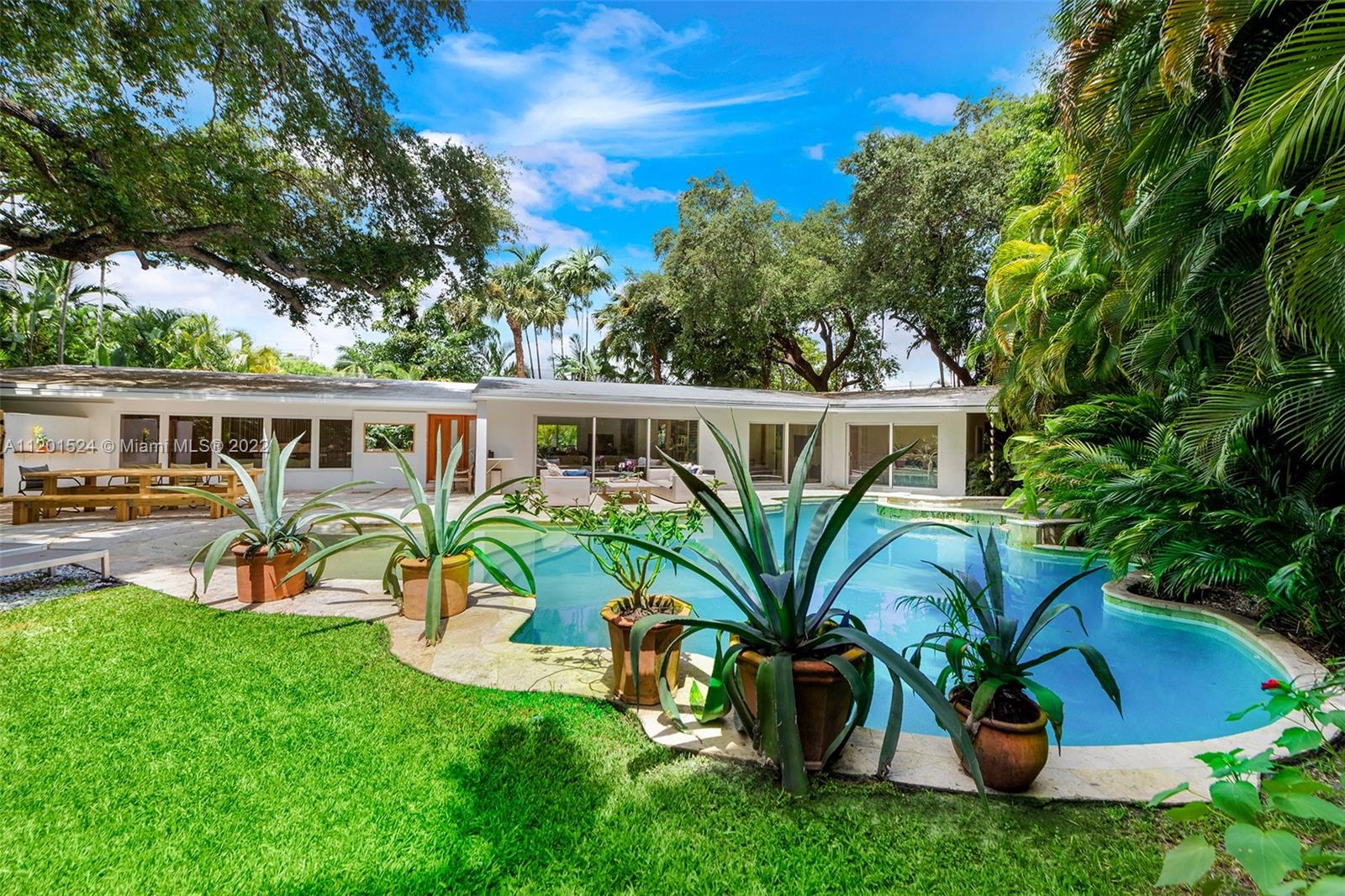 Beautifully updated, 2,464 SF, 4 bedroom, 3 bathroom, midcentury modern home in the most prestigious part of Miami Shores. This private, tropical, 12K+ SF lot sits under majestic oaks overlooking a heated, free-form pool with jacuzzi, and waterfall. The open floor plan features large rooms with floor-to-ceiling impact sliding doors throughout that exaggerate the lush greenery that surrounds the residence for a true indoor/outdoor living experience. Gourmet kitchen with quartz countertops and VIKING gas stove. The previous owners converted the 2 car garage into the new master wing with permits, it features luxurious walk-thru closet, custom dual sink vanity, oversized shower, and separate extra-large soaking tub with a view of your private tropical oasis! 2 A/C units Gas water heater!