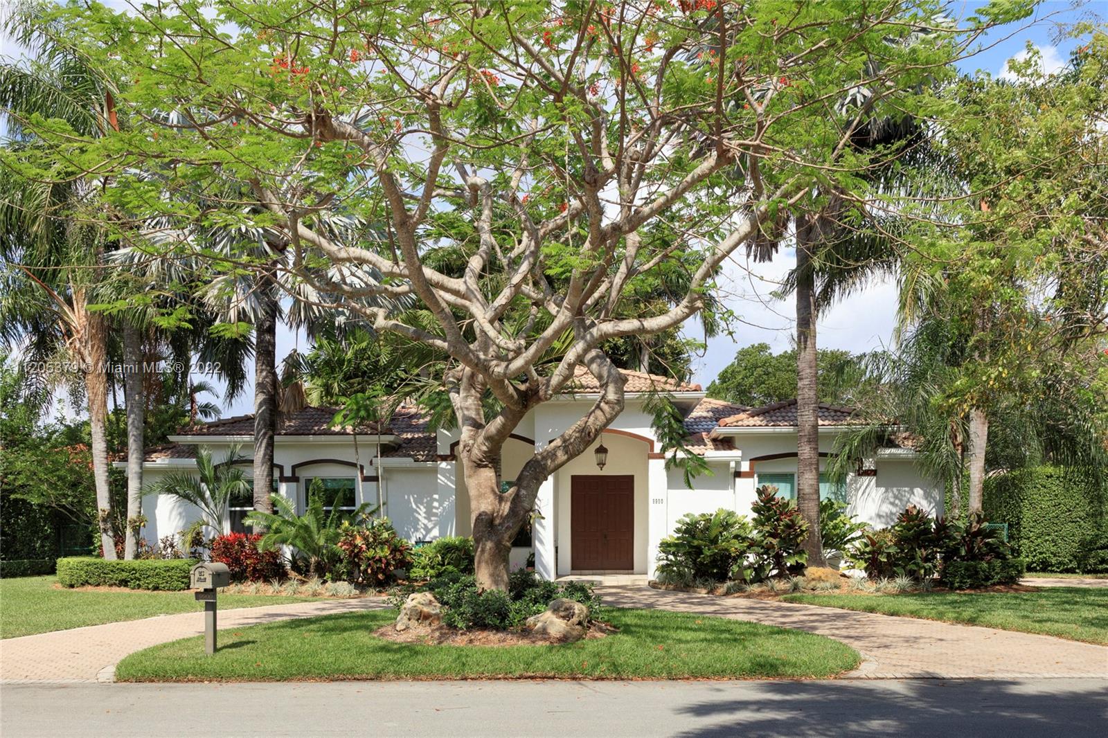 Set on the corner of a quiet North Pinecrest cul-de-sac with views of one of Miami’s largest banyan trees, this inviting home is too good to miss! As you step into the formal foyer, be enchanted by the high vaulted ceilings and bright open floor plan. With formal living and dining rooms, a family room, and a large kitchen with a breakfast area, there’s plenty of space for family and friends. From the kitchen or family room, step out on to your covered terrace and enjoy the pristine backyard with fountains into the pool, tropical landscaping, and 25+ orchids hanging from the trees. Zoned for Pinecrest Elementary with top private and public schools nearby. Impact windows/doors, whole house generator, two-plus-car garage, and two paved driveways complete this picture-perfect home.