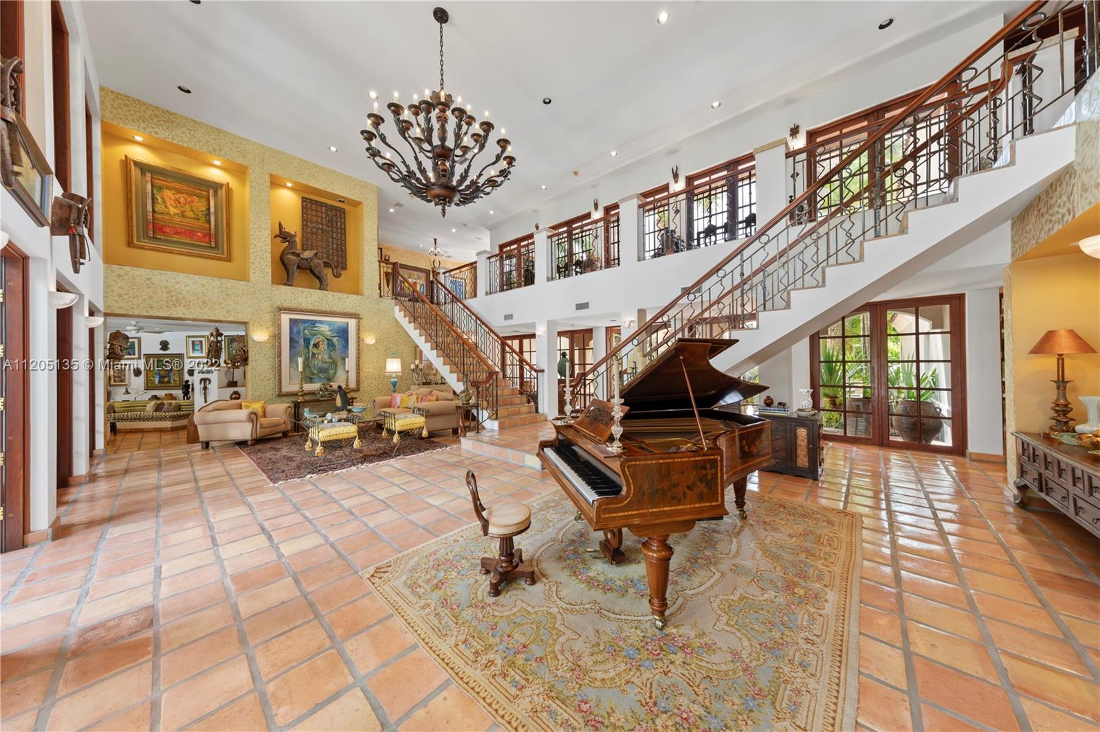 The foyer opens to a 22' high formal living with twin staircases......20 sets of mahogany French doors shower natural light into this space.