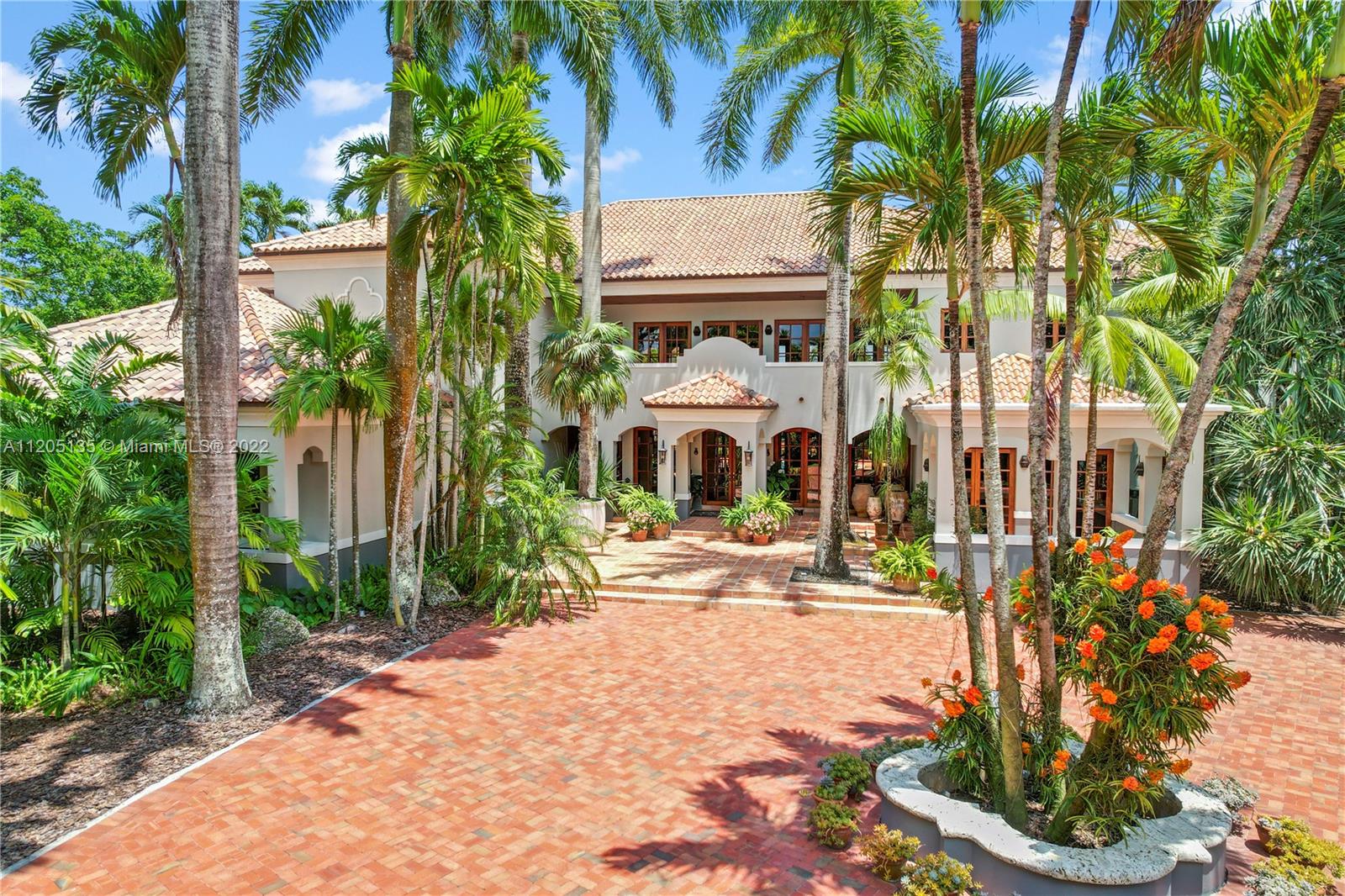 Partial view of main entrance with circular quatrefoil motor court. This emblem will be seen thru out the compound. The grounds are walled in with an old coral wall adorned with ironwork and red bougainvillea. You are greeted by 2 massive solid mahogany gates that sets the tone for this estate. The use of natural products, quality, foresight will provide the longevity desired. This estate will remain for generations.