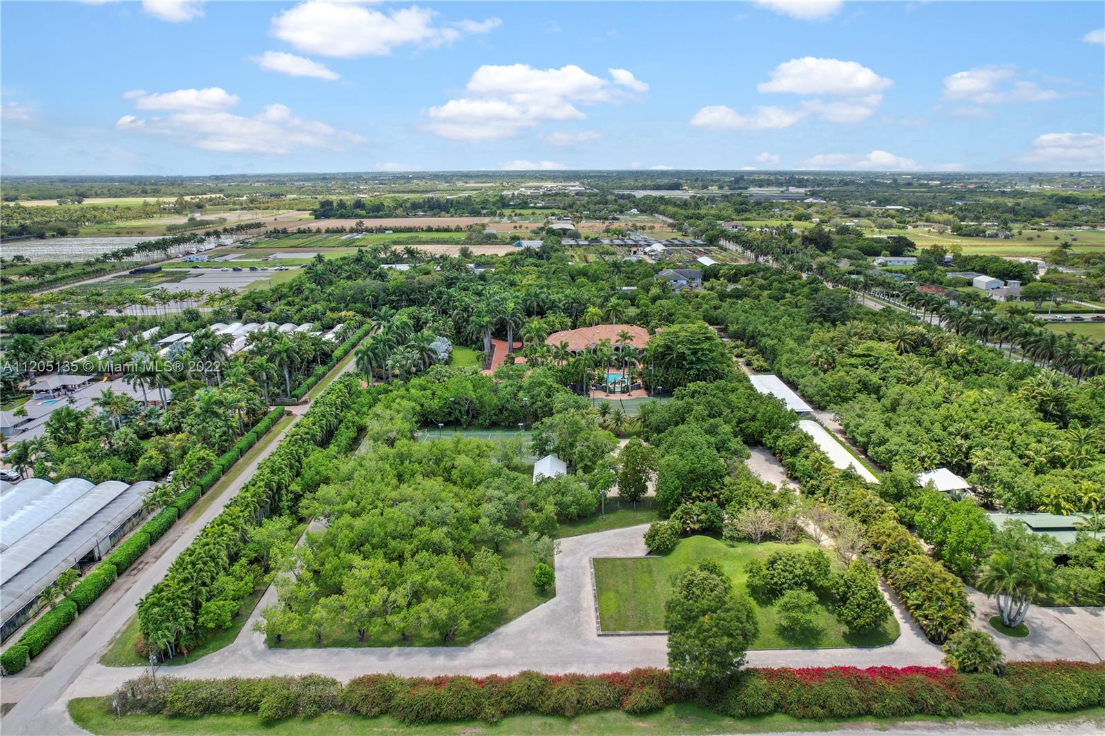 Aerial view showing grove, pathways, vegetable gardens for farm to table, tennis court, volleyball court, & basketball court, loads of parking off service road, adorned by bougainvillea & 100