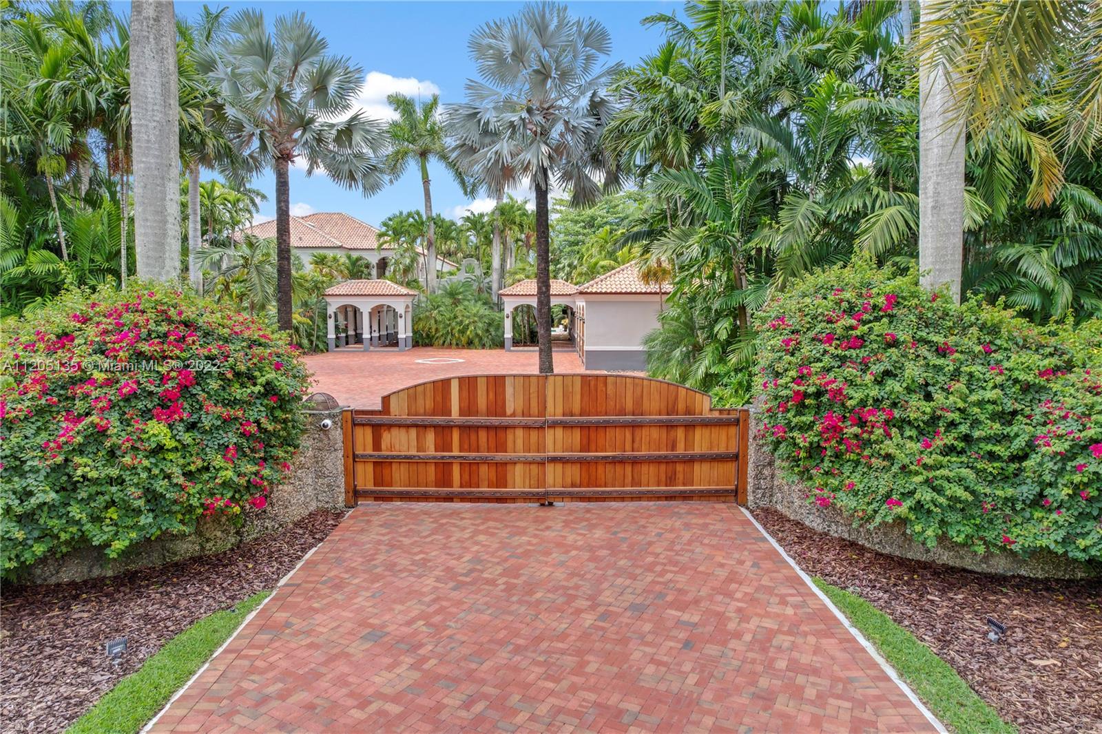 2 Massive mahogany wood gates surrounded by a 100 year old coral rock wall with ironwork leads the way in to this lushly landscaped tropical estate. (Service entrance pictured)