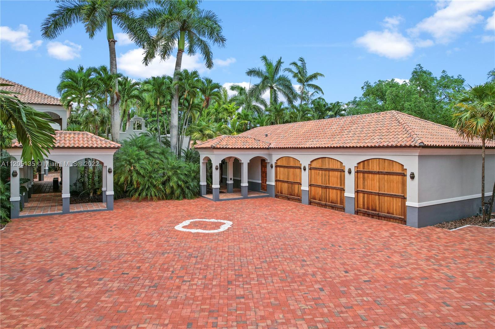 Detached 3 car garage w/pavers that include a 2nd large motor court. Notice the emblem, the 4 arch's which reflect the quatrefoil, a part of the main design of this contemporary villa. The covered breezeways provide an enjoyable experience navigating the estate with ease.