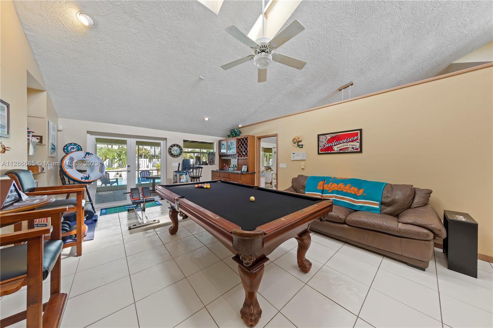 LARGE FAMILY /GAME ROOM W/ FRENCH DOORS LEADING TO POOL. IN DISTANCE IS THE WET BAR