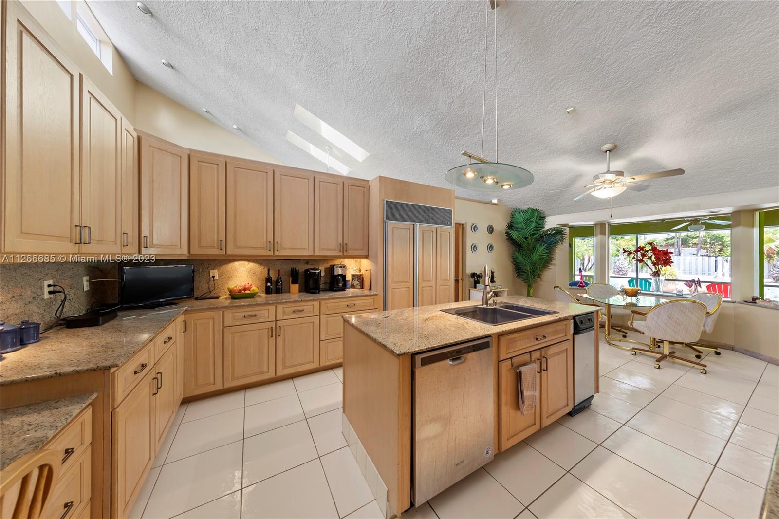 LARGE & FULL OF LIGHT CHEFS KITCHEN W/ CUSTOM CABINETS, CENTER ISLAND & BREAKFAST NOOK. VAULTED CEILINGS AND FRENCH DOORS LEADING TO POOL