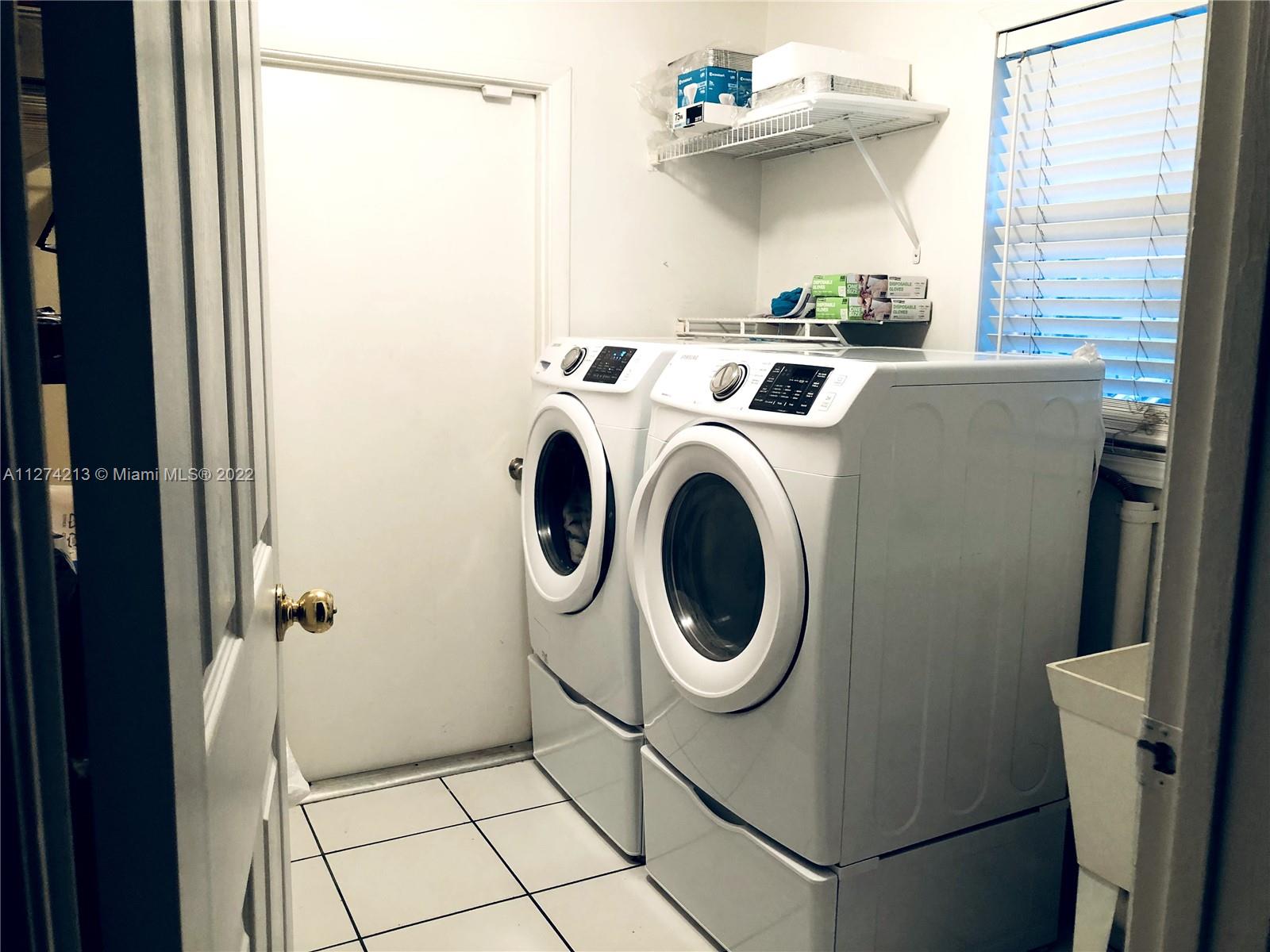 Convenient indoor Laundryroom with plenty of shelves and pantry and tub.