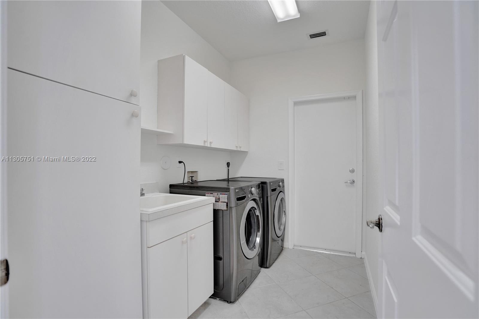Spacious laundry room with stainless front load washer and dryer, built in sink and lots of storage cabinetry. Also freshly painted.