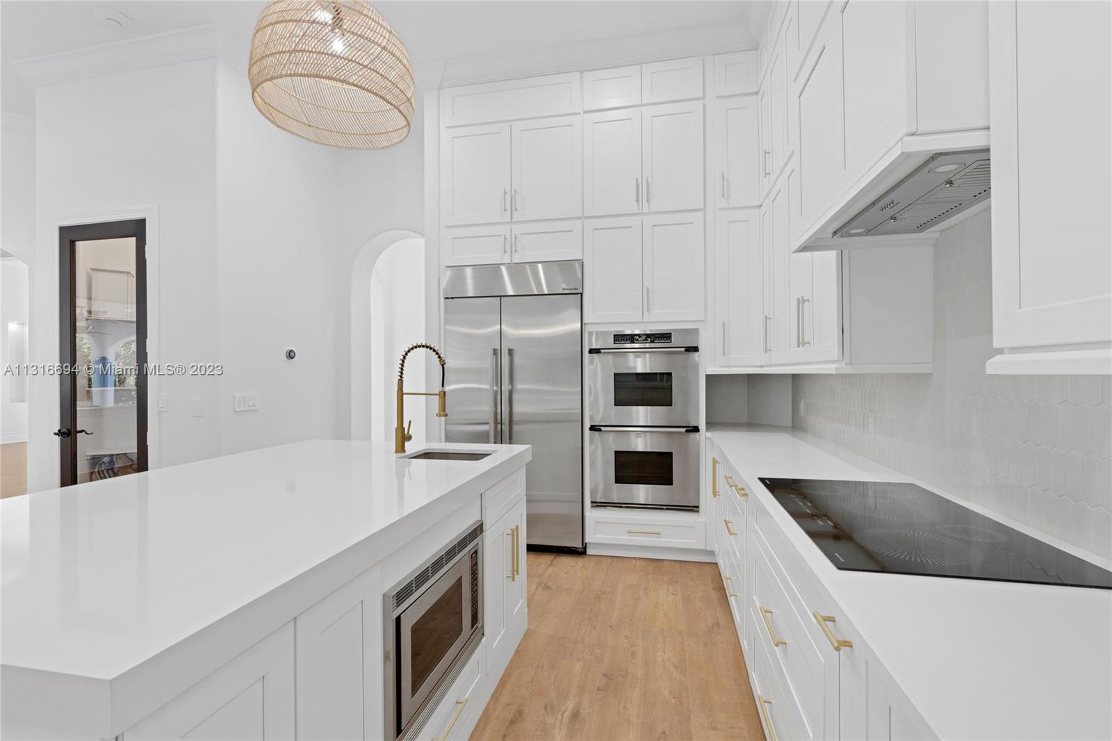 This masterpiece combines functionality and style, with professional-grade stainless steel appliances, cabinets to the ceiling, slabs of white quartz counters, and a grand island.
