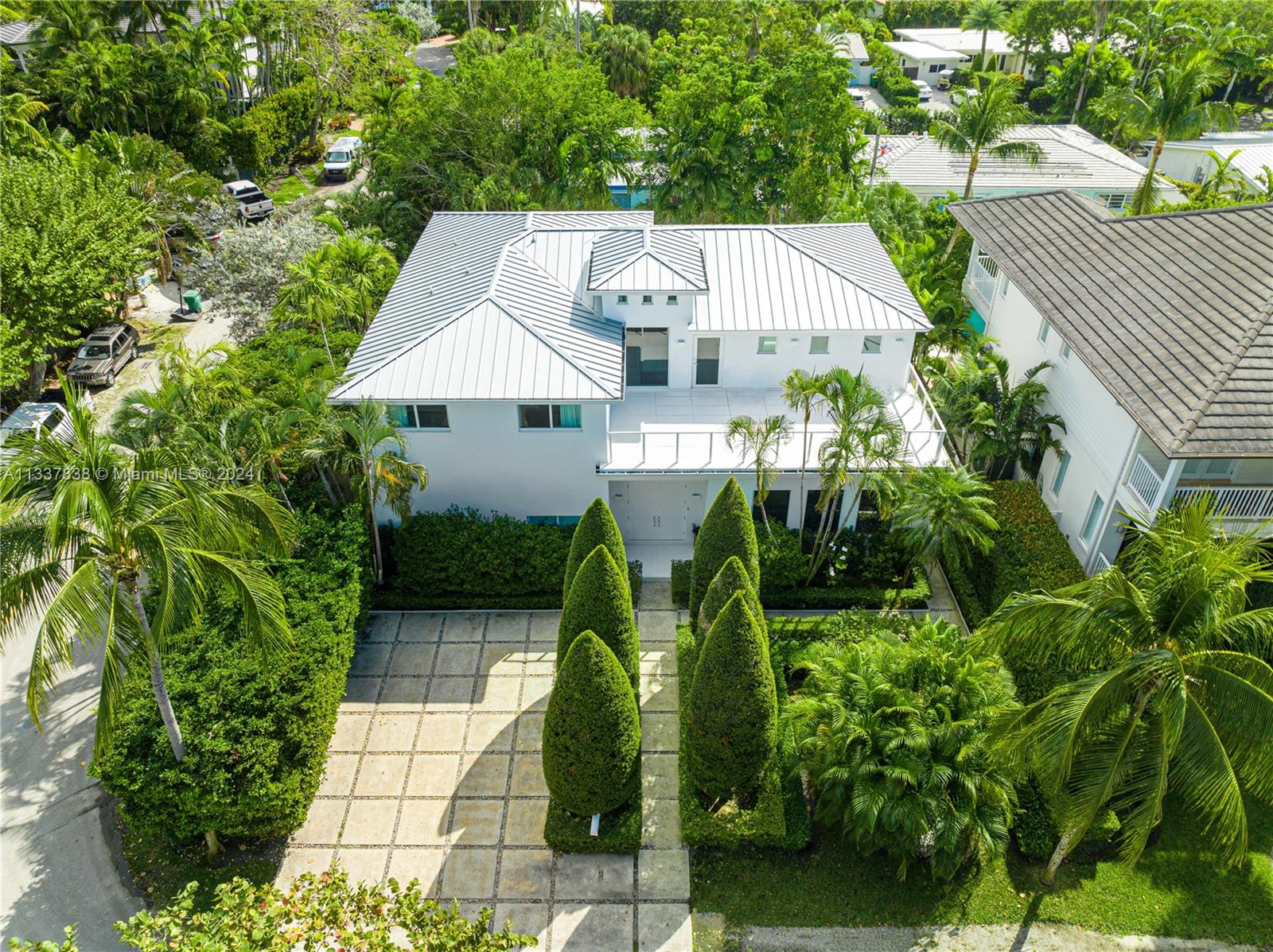 ENJOY THE PEACEFUL AESTHETIC OF THIS TREE-LINED KEY BISCAYNE MiMo STYLE FAMILY ESTATE WITH SOARING 25 FT CEILINGS ON OVERSIZED CORNER LOT! 4,021 SF Home Nestled in Nature w/ 5 Bedrooms + 4.5 Baths on Large 8,000 SF LOT. Light & Bright Grand OPEN Livingroom Boasts Double Height Ceilings w/ Recessed Lighting & Lineal AC Diffusers. Family Room & Dining Area flow into the Modern Eat-in Chef’s Kitchen in White featuring an Oversized Island, Miele Stainless Steel Appliances & Wine Refrigerator w/ Windows overlooking Lush Greenery. White Staircase Leads to Large Primary Suite w/ 2 Walk-in Closets + 2 Terraces. Primary Bath Wrapped in White w/ Floating Tub & Steam Rainshower. Outdoor Entertaining & Lounging Areas sit on White Wood Deck. Pool wrapped by Manicured Gardens for the Utmost of Privacy.