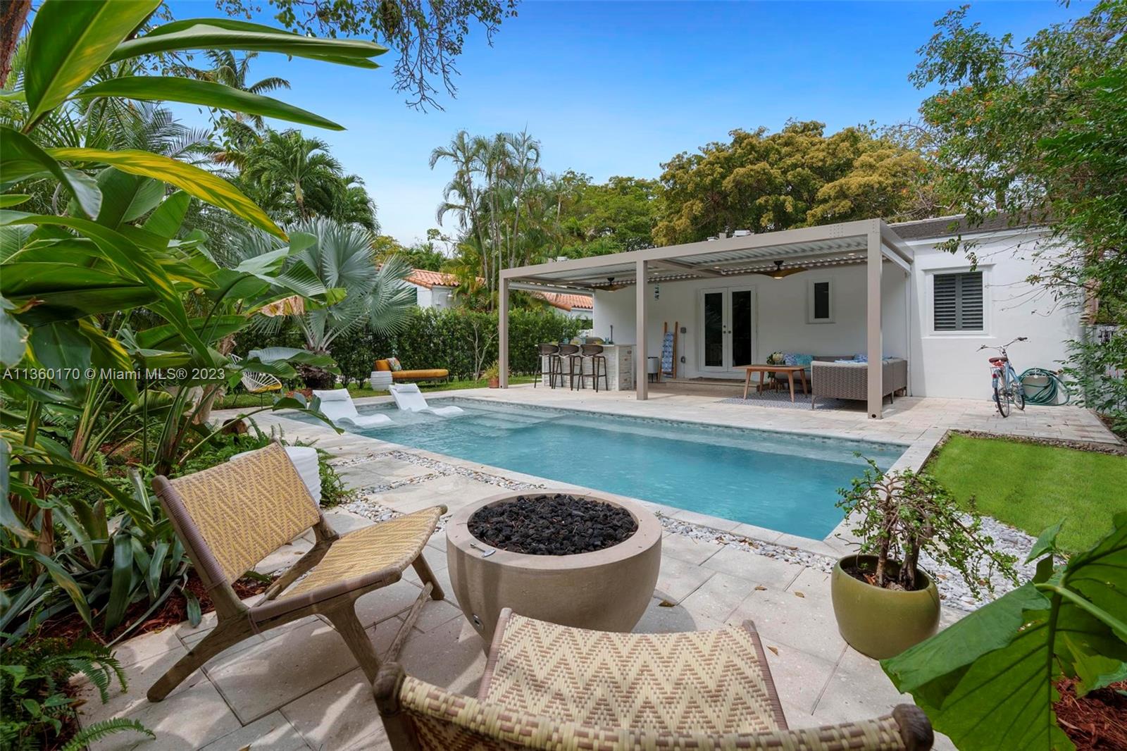 Welcome to your new home, a true tropical oasis, featuring a salt water pool where you can lavishly entertain rain or shine underneath the retractable pergola featuring a built-in outdoor grill, refrigerator and bar. Lush greenery and mature trees provide privacy and tranquility.  This  Coral Gables 2/1 home is a perfect blend of modern amenities and classic charm featuring a chef's kitchen; Miele appliances; quartz countertops; Waterworks bathroom fixtures; and original fireplace.  The living room is bright and airy, with large windows that let in plenty of natural light. The living room seamlessly transitions into the dining area and open kitchen which is perfect for hosting family gatherings and dinner parties. Garage converted as a den/office and laundry room. New roof 2017, HVAC 2020.