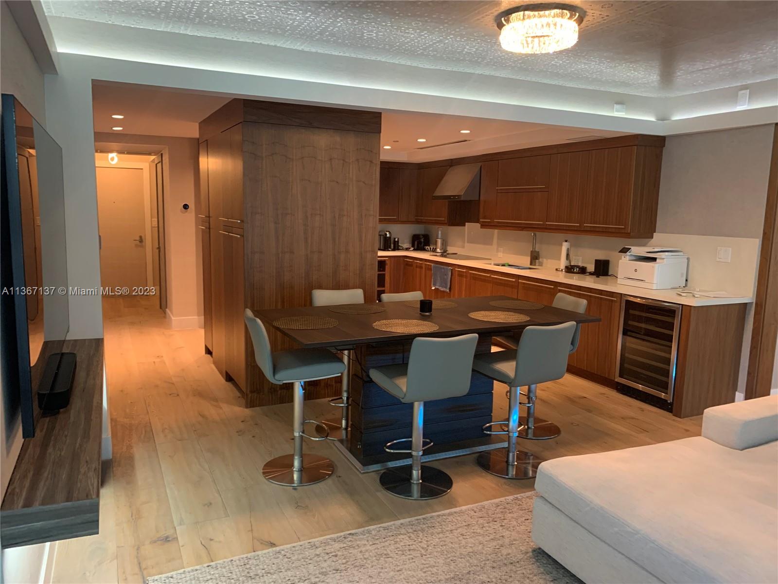 Dining room with huge flat screen tv and kitchen in the background.