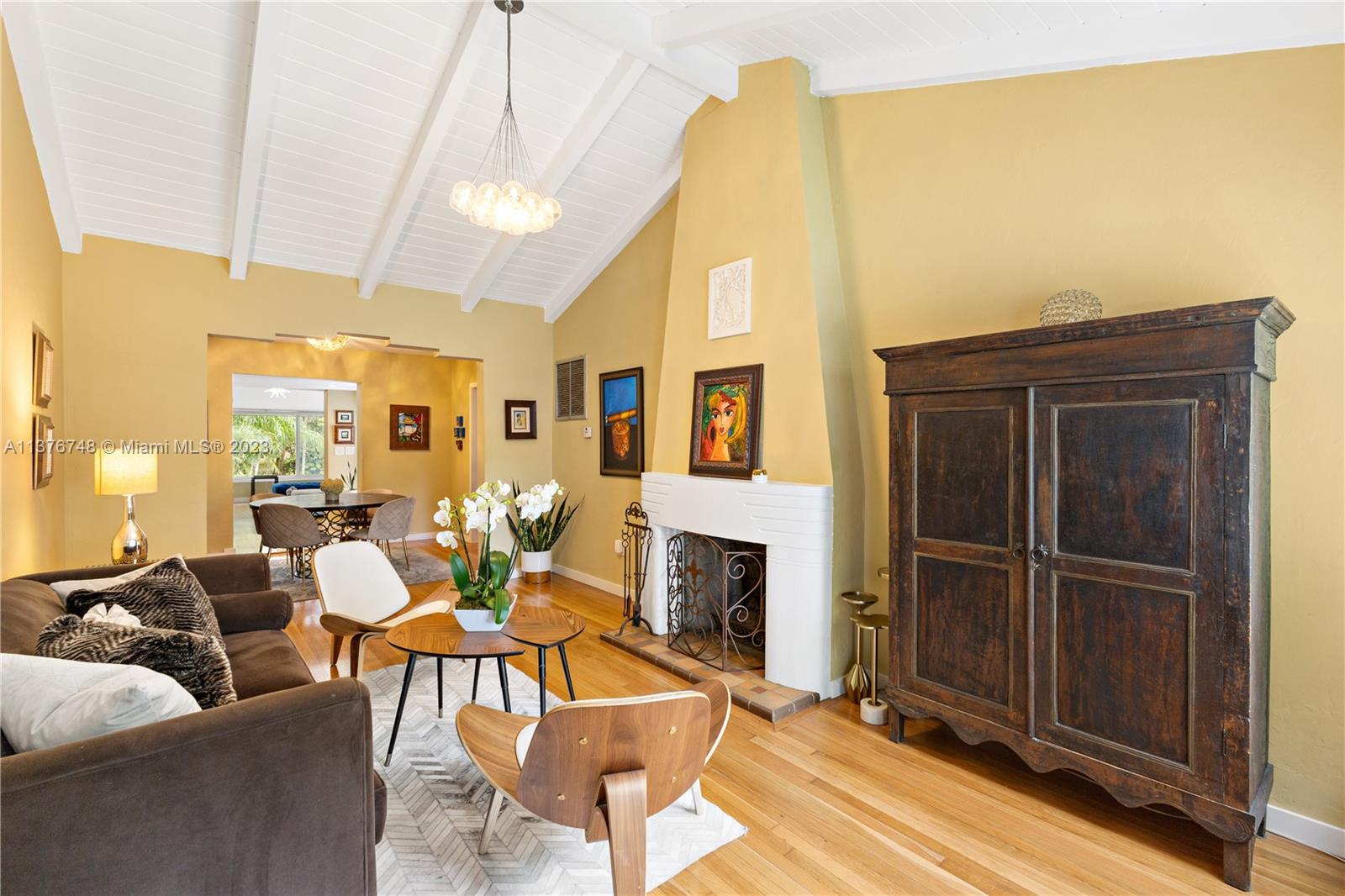 Spacious living room with tall cathedral ceilings welcome you and the classic fireplace and vintage plaque give a quintessential Coral Gables feel.