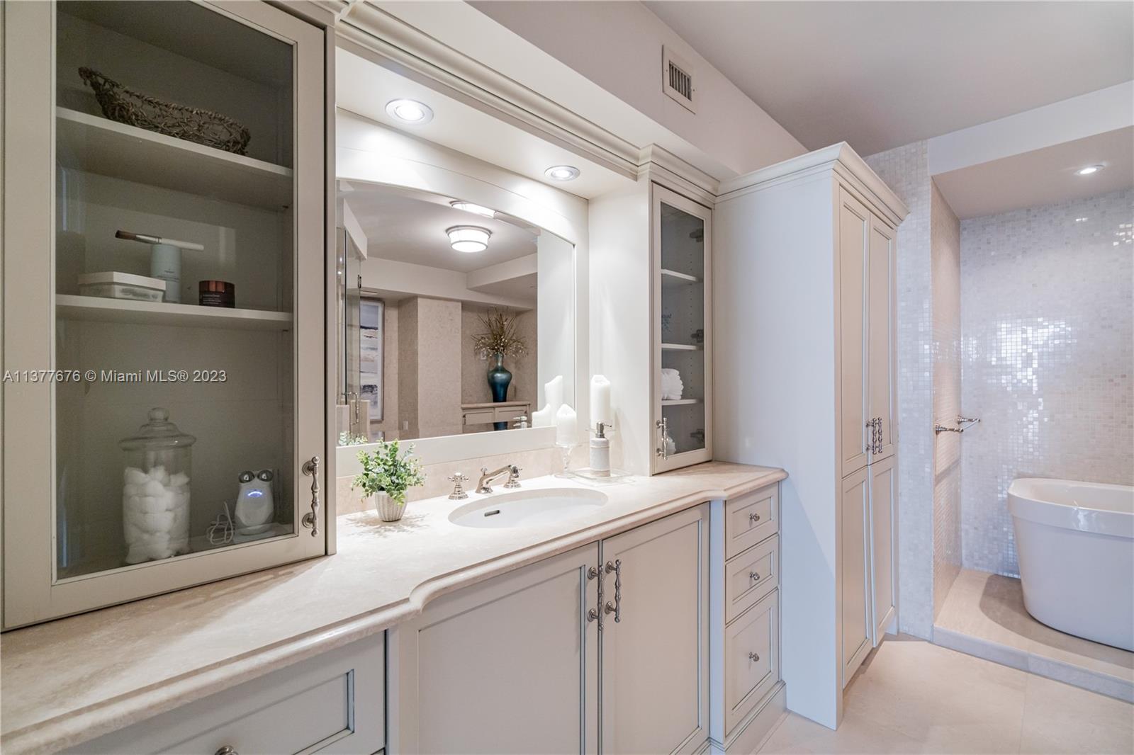 Stunning bathroom showcasing an elegant vanity area, free-standing Jacuzzi Tub, and oversized glass-enclosed Steam Shower.