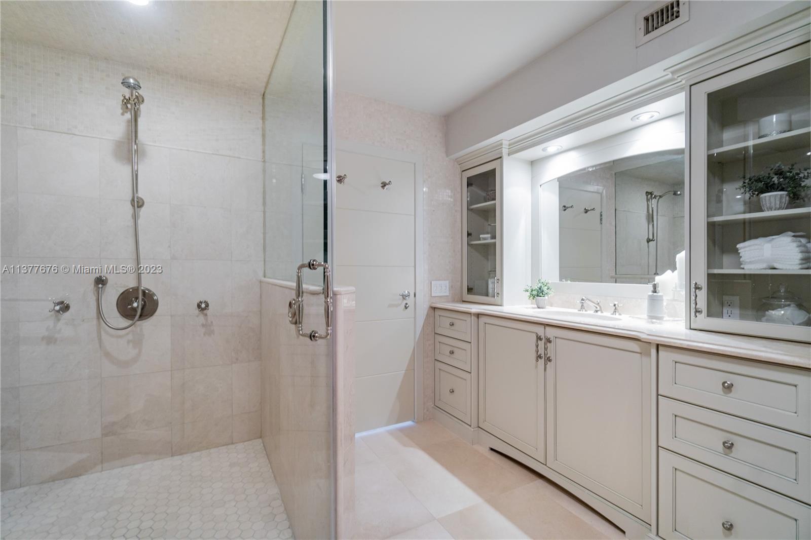 Stunning bathroom showcasing an elegant vanity area, free-standing Jacuzzi Tub, and oversized glass-enclosed Steam Shower.