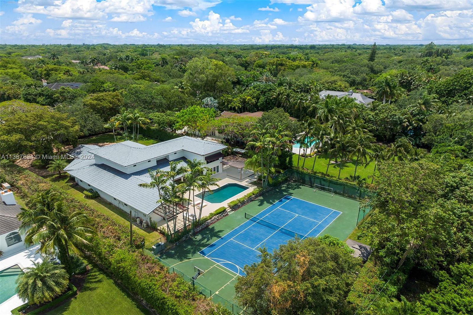 Discover an impressive one-story home in North Pinecrest with a tennis court. Welcomed by a grand foyer leading to a spacious formal living room with high ceilings, creating an inviting atmosphere. Discover spacious entertaining areas: formal dining, cozy breakfast nook, and open-style kitchen connected to a large family room. The family room boasts a convenient built-in bar and enjoy a home theater room on the second level for entertainment. Retreat to the renovated master suite with a spa-like bath and private outdoor deck. The backyard offers a tranquil ambiance with a pool, tennis court, and summer kitchen. Other features include a versatile playroom/den as a converted 2-car garage, impact windows/doors, and proximity to top-rated schools.