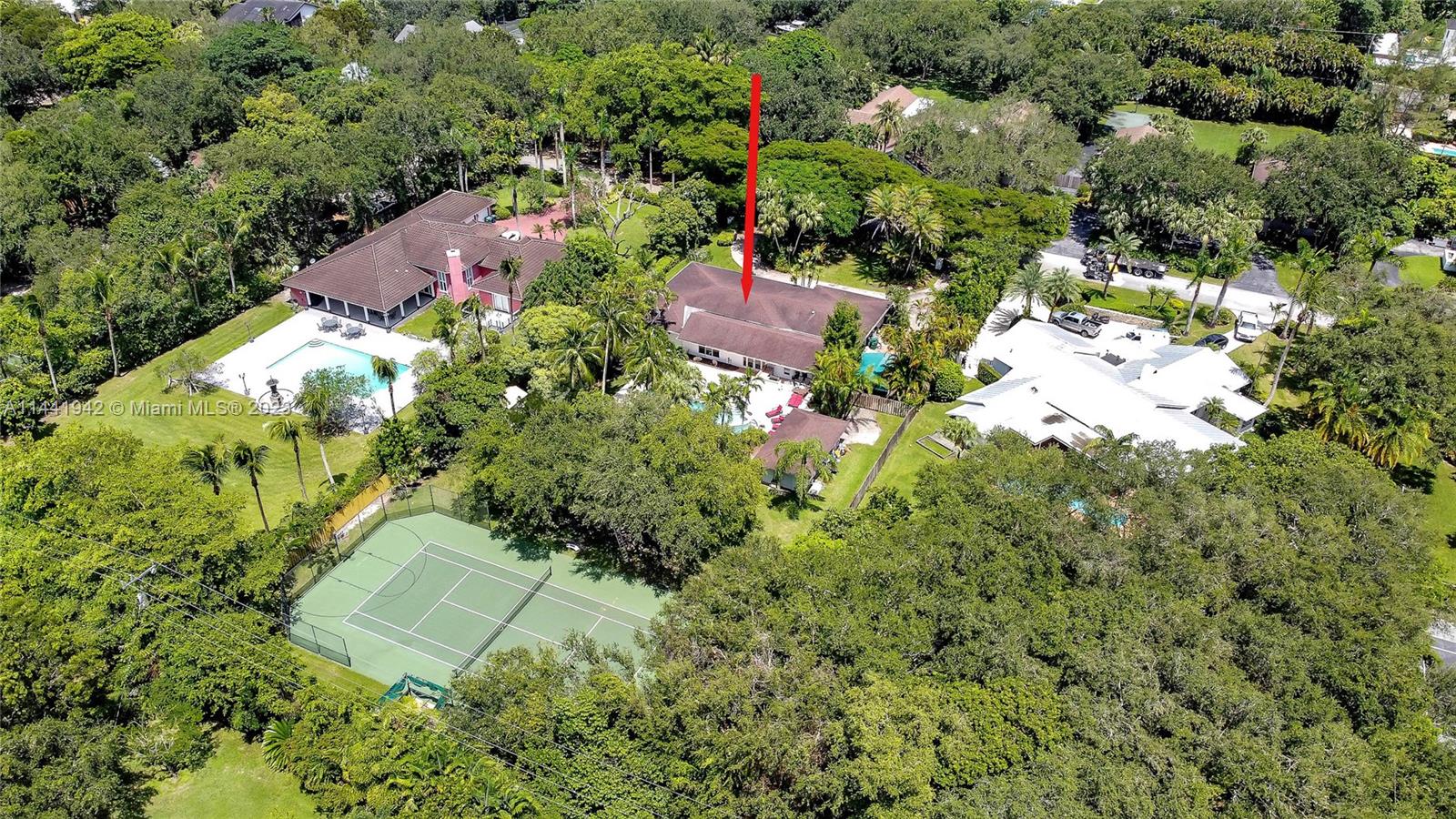 Beautifully appointed & updated, 4 bdrm/4.5 bath home on an acre in North Palmetto Bay. Wonderful formal living rm. Expansive family rm w/ virtual fireplace, vaulted ceilings opens to formal dining. Bonus/game room. Updated, modern kitchen w/ sleek cabinetry, quartz countertops, island w/ seating, wine chiller, serving area, abundant storage. Wood-style polished tile floors.  Spacious primary bdrm overlooks the lush grounds, has luxurious, oversized bath. Exceptional fenced backyard space w/ summer kitchen, pool, keystone patio, fantastic, covered cabana w/ full bath. Sports court perfect for a game of tennis, pickleball or basketball. Shed, security cameras. Impact windows & doors. Indoor laundry. Paver driveway, 2 car side entry garage modified for storage + carport.