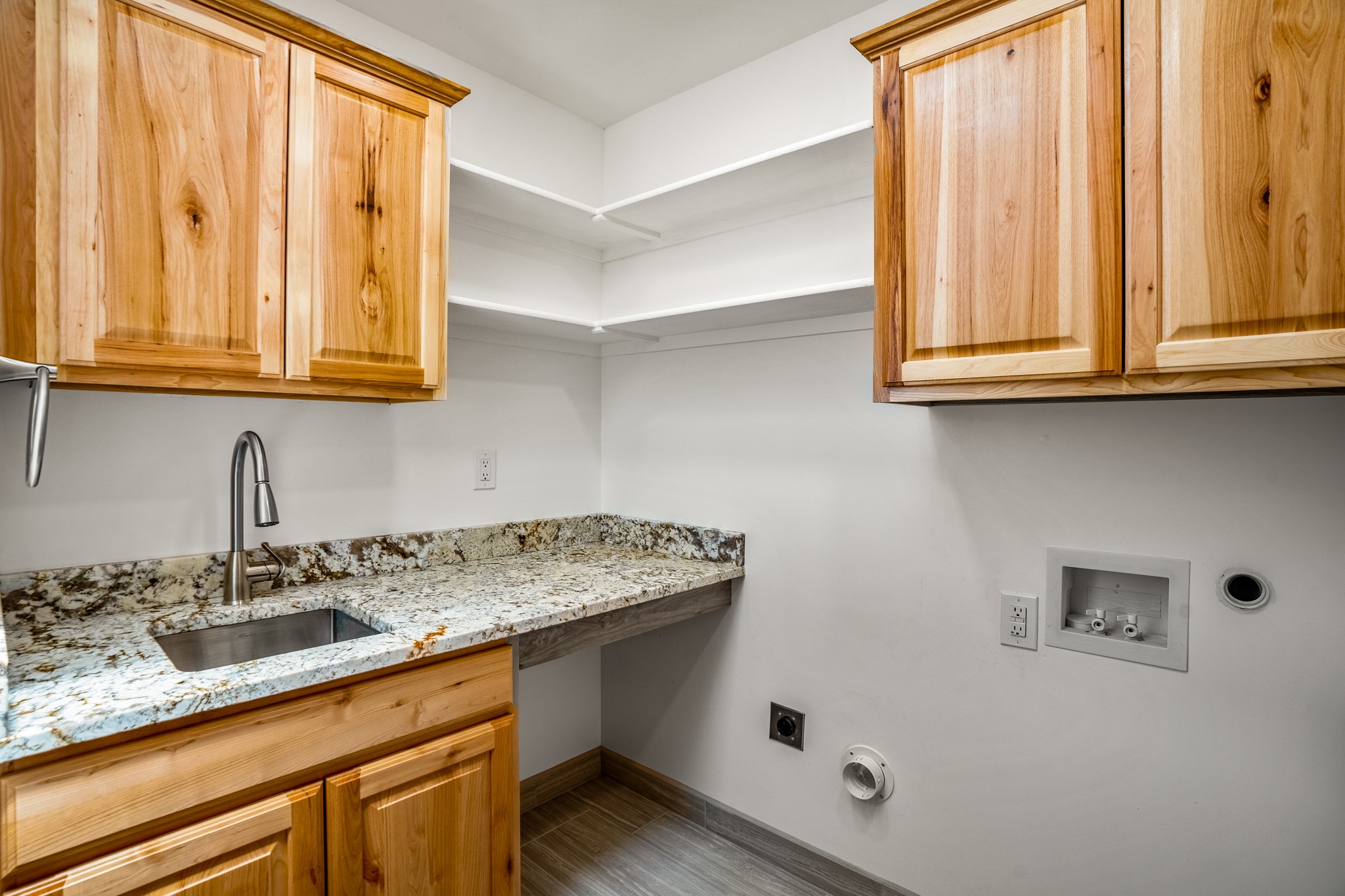Laundry room with sink, plenty of counter space, cabinets and shelves.