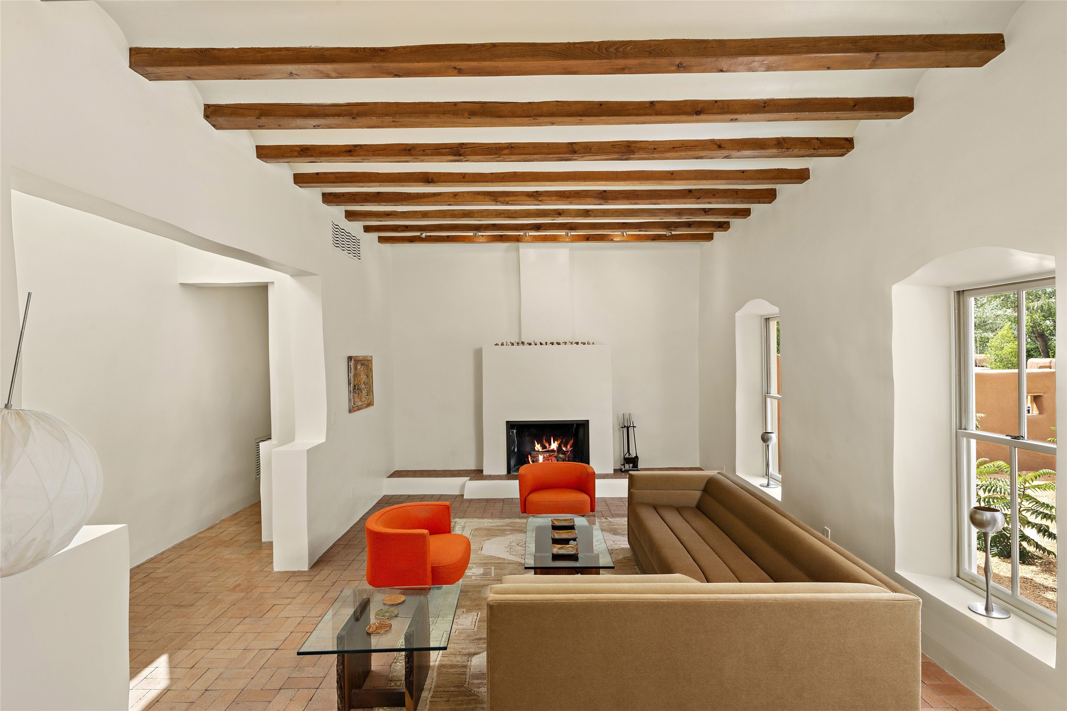 The living Room has high beamed ceilings & adobe walls with a raised fireplace