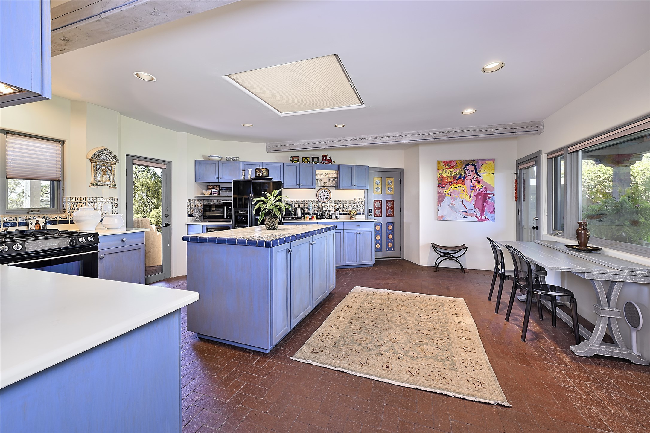 Cheerful, warm, and inviting, the home’s delightful second kitchen radiates the color and charm of Santa Fe. Vibrant ceramic tile accents the backsplashes and counters, including the center island.