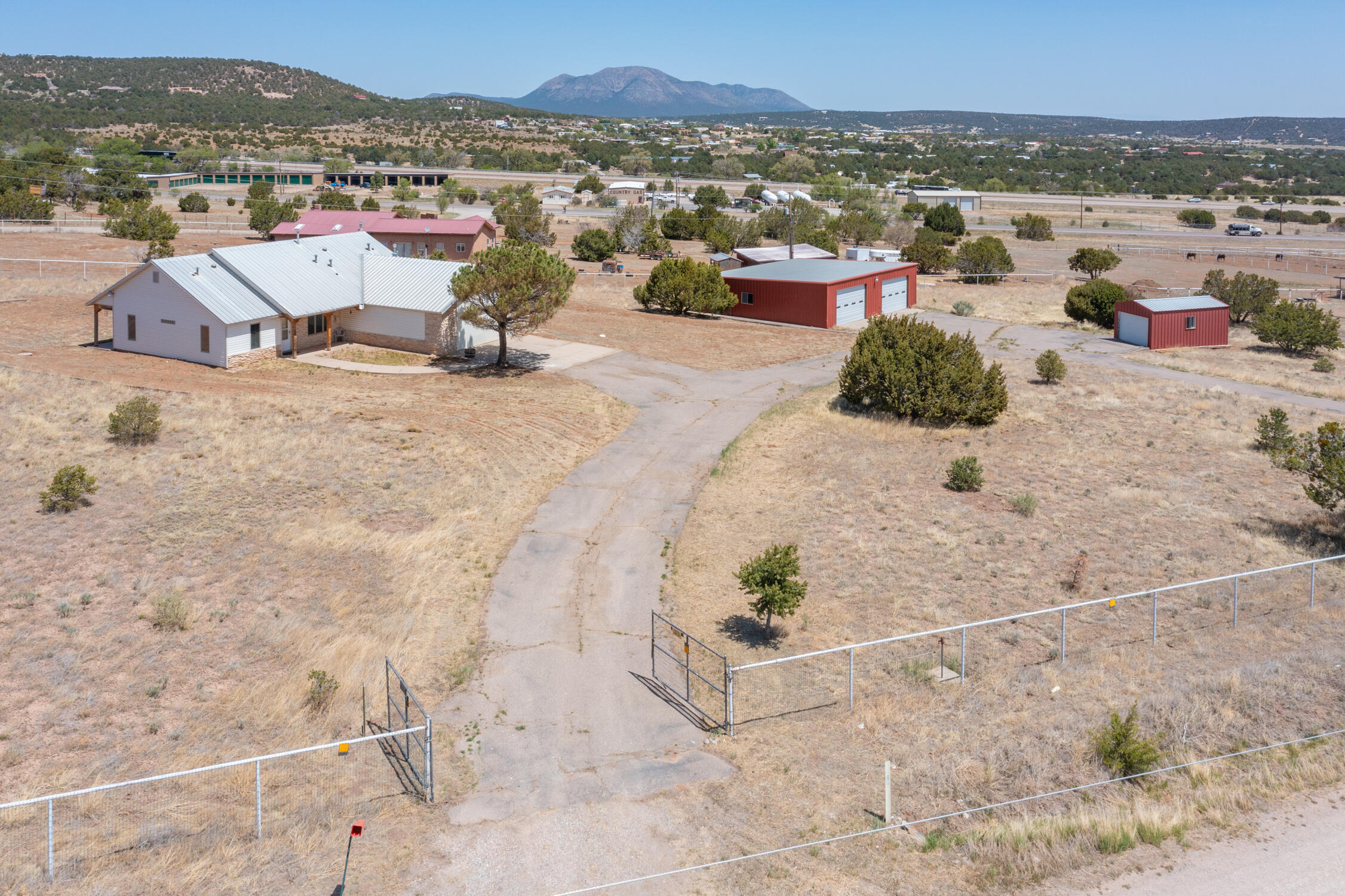 Just over 2 acres, this ranchette is completely fenced and ready for your animals or toys.  Just a 30 minute drive to downtown Albuquerque, This home offers lots of space and mountain views.  Besides the 25 x 27 attached 2 car garage, property has an approximately 38 x 40 ft out building with electricity that will garage 4 more cars/tractors  or make a great barn or workshop.   Plus has an additional 10 x 20 storage building.. Home has upgraded wood windows and accents in the living area.  Metal roof and Wrap around porch helps keep you cool in summer.  Vented for wood burning stove in Family room. New W/H Home is on the Entronosa water system and the Septic inspection done .  Besides fresh paint and new floor covering this place  is a real beauty and will make a special one to call home!