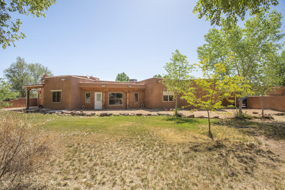 Charming custom-built 4-bedroom home set in the green belt heart of Corrales, w/ easy access to shops, restaurants & walking trails. This light-filled home captures the very best in pueblo style, including raised tongue & groove ceilings, numerous nichos, exposed vigas & a kiva fireplace designed by Al Knight. Beautiful ceramic tile & engineered hardwood floors grace the interior (no carpet). Kitchen & bathrooms boast granite countertops. Huge master suite has large walk-in closet. Refrigerated air. Spacious garage features epoxy floors w/ ample storage. Two wells allow for easy irrigation. Property is gated for privacy & a stone's throw to all Rec center amenities. A true Corrales treasure w/ an easy commute into town. Bring your animals & green thumb to this Corrales country treasure!