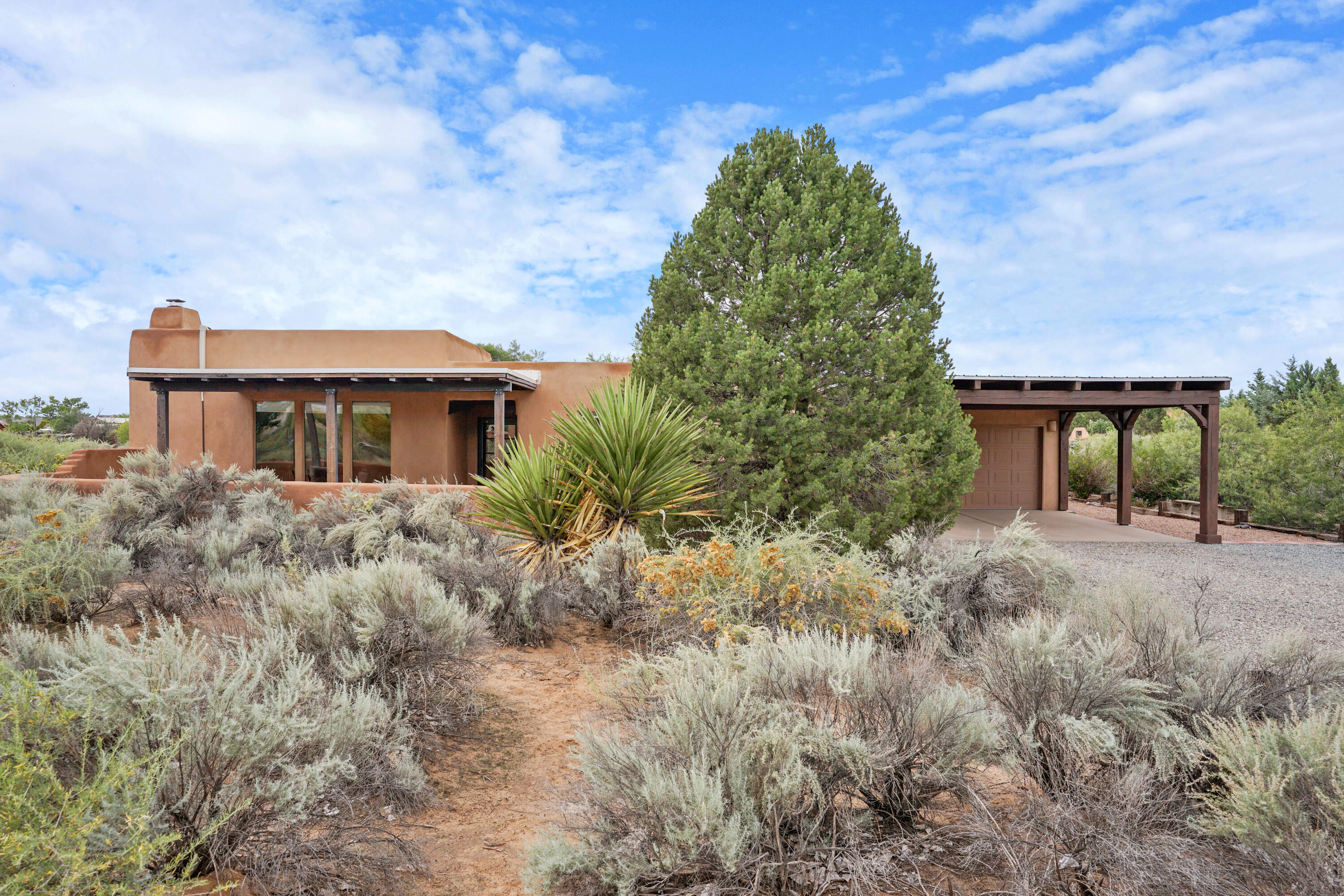 Don't miss out on this gorgeous southwestern style home in Corrales! This home features mountain views, viga-beam ceilings, and decorative wood beams throughout. Cozy up next to the kiva wood-burning fireplace or enjoy the views from under the covered patio. Bright, spacious kitchen with dining area, custom cabinets, double-oven gas range, island, and pot rack. The bonus room off the main house makes a great home office or craft room that is fully heated and cooled. Home includes a newer AC/heat mini-split system to complement baseboard heating. Other features include a 2-car garage plus carport, a TPO roof, a whole-house water filtration/soft-water system with RO filter in kitchen, a rainwater catchment system, chicken coop, utility shed, two fenced garden areas, and an outdoor sink.