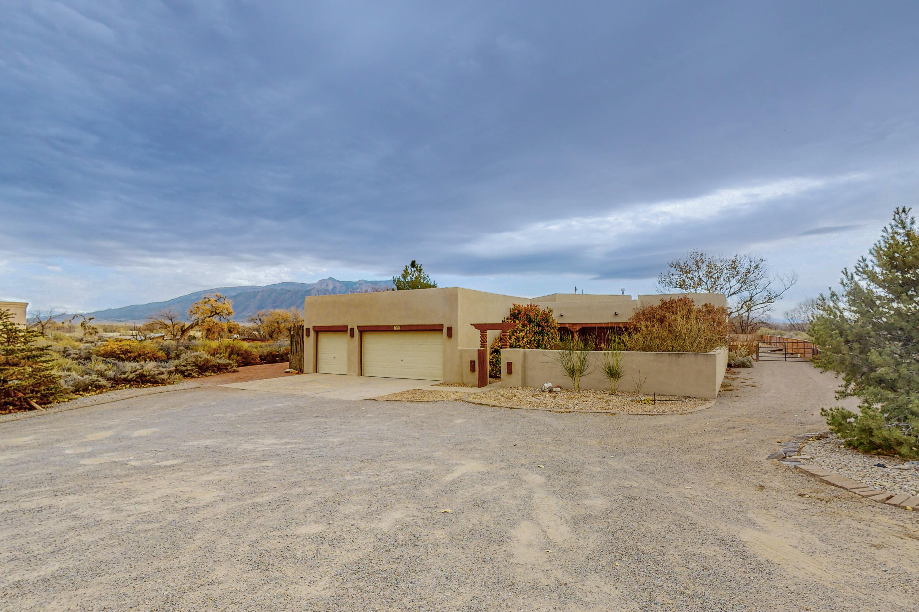This lovely southwestern style home boasts a spectacular view of the Sandia Mountains unobstructed by any roads or buildings as you look across the tops of the Corrales green belt and enjoy the colors of the 4 seasons from the covered portal that lines the back of the home or from the windows of the spacious spa like master suite (with fireplace and jetted tub) or from the carved pillars. beamed ceiling and cozy gas fireplace of the sunken living area or from the window lined dining room. Located on a private Cul de Sac with 3 other homes, the house itself is very private as no other property is visable from all but the kitchen, which looks out on the beautifully landscaped entry. This home has beautiful flooring and newer windows with  wood blinds thru out. It is spectacular! Come see it!