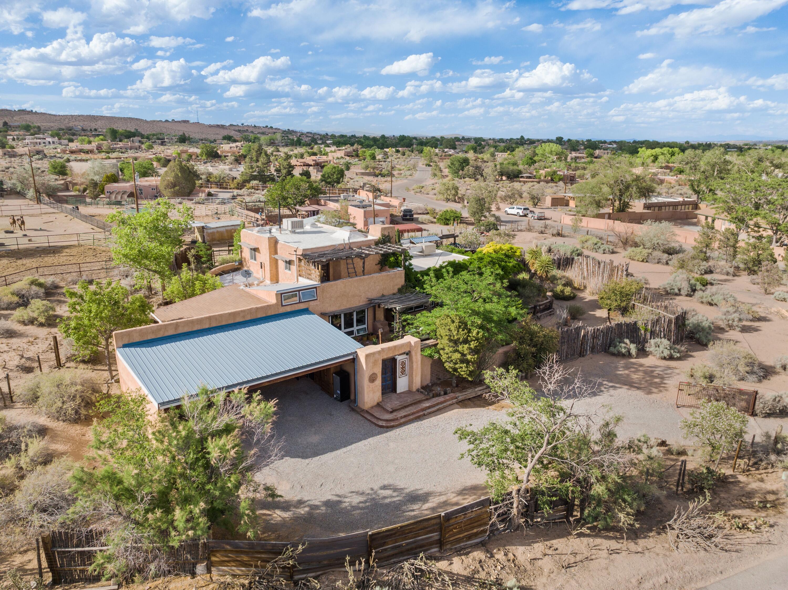 A breathtaking one-of-a-kind contemporary southwest home in the heart of Corrales! Enjoy mountain VIEWS from multiple outdoor patios w/ pergolas, vines & Wistaria surrounding! Unique touches throughout include nichos, exposed wood & adobe, plaster walls & brick flooring! Open floorplan w/ tons of natural light and all bedrooms separate from eachother make it suitable for multi-generational living, Airbnbs or families. Primary guest suite on main level w/separate entrance & a second primary suite upstairs w/balcony & stunning mountain VIEWS! Gourmet kitchen w/ kitchenAide stainless steel appliances that include a double oven & wine cooler-perfect for entertaining! .75 acre lot is very private as its fully fenced & spacious side yard allows space for RV or boat. A truly enchanting oasis!