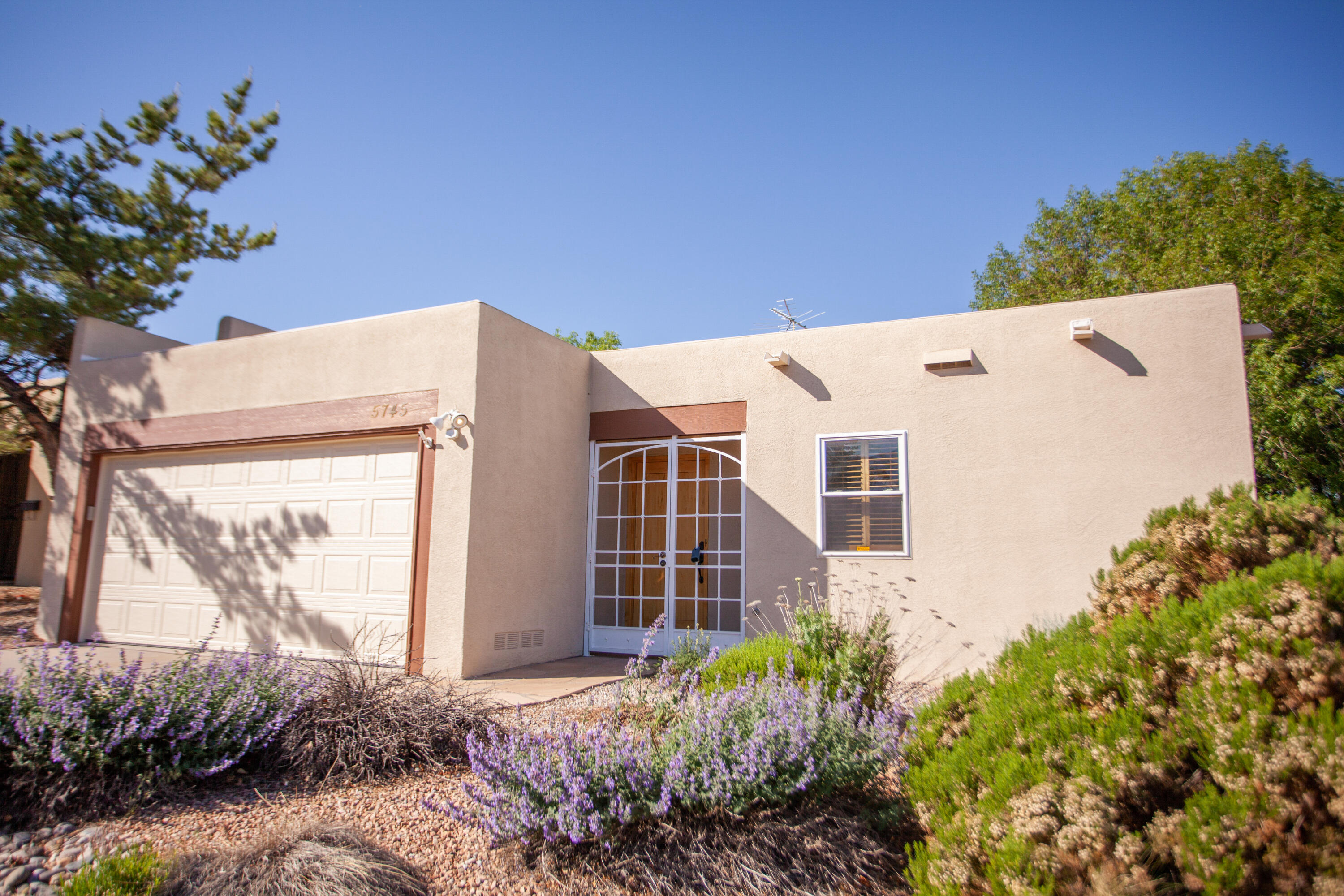 Location is everything with this updated townhome in the far NE Heights near Juan Tabo and Academy. Cathedral ceiling in the large living room with a wood-burning fireplace with gas log starter. LR leads out to a covered porch and a large backyard on a corner lot with dog runs. Gorgeous views of the Sandia mountains outside the front door. Updated bathrooms, appliances and combo unit; furnace/refrigerated air. Original owner since 1983 with incredible pride of ownership. These photos are a snapshot into this pueblo-style updated single story home with no steps. Seller is installing carpet in the first bedroom and a new hot water tank. Doors can be installed on the office if you want to make it a bedroom. It does have a closet.