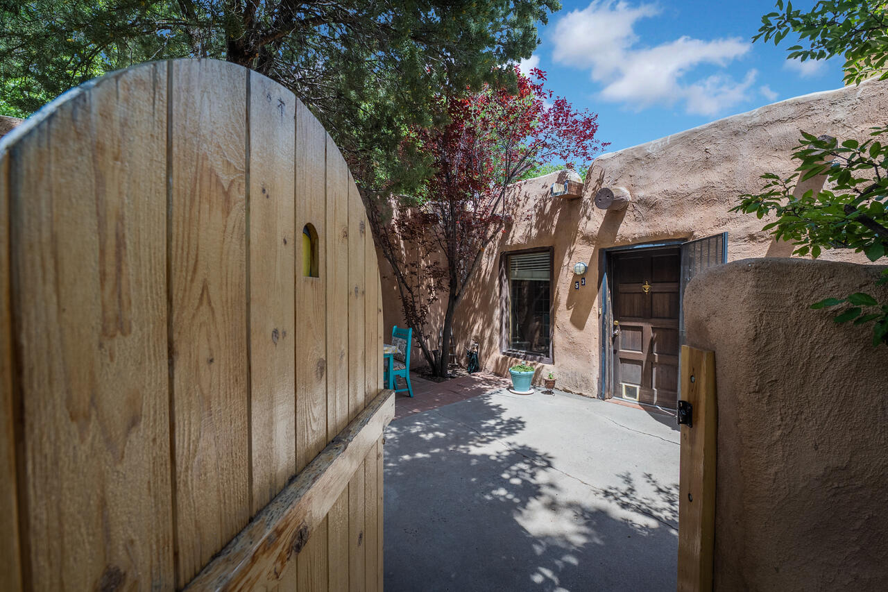 Two bedroom authentic adobe home in Cimino Compound, an 11 acre planned unit development on historic Rio Grande Boulevard in the North Valley. Brick floors & high ceilings w/ vigas beautifully stripped to the natural wood. Kiva fireplace in the great room. Updated bath (2023), recoated roof (2022), skylights (2018) and hand-crafted front gate (2017). A well-maintained unit w/ one of the largest patios in this quiet, private compound. Cimino has a pool, clubhouse, fitness center, sauna & dog park. It boasts vegetable, flower & xeric gardens & gate access to the acequia & walking trails. HOA dues includes amenities, insurance, sewer, water & gas utilities (heating and hot water).  Cimino Compound is directly across from Flying Star restaurant, boutiques & the independently-owned Bookworks.