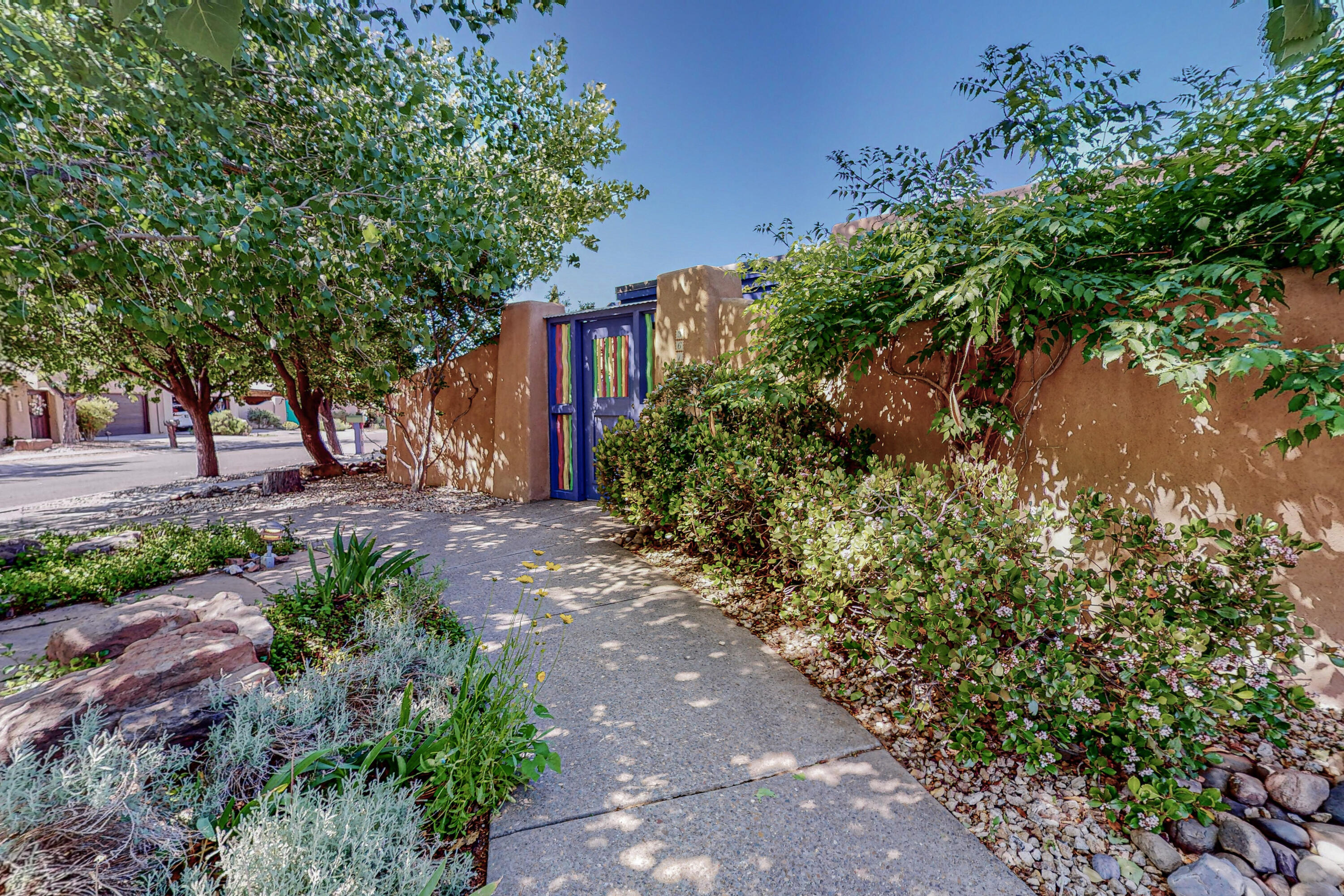 Welcome home to the beautiful North Valley of Albuquerque. Sited on a small cul-de-sac off of Rio Grande Blvd., you will enter the private, landscaped courtyard to the front door of this beautiful Pueblo-style home. Features include 2 primary bedroom suites with full bathrooms and garden access, an additional room that can be used for a bedroom or home office, a large and bright living room with a wall of windows and built-in bookcases, designated dining area, a separate large and open kitchen and family room complete with back garden access, brick floors and fireplace. Enjoy beautiful vistas of the courtyards and private landscaped back garden complete with a flowing pond. Convenient location near Flying Star and El Patio, Bookworks, bosque hiking trails and Nature Center.