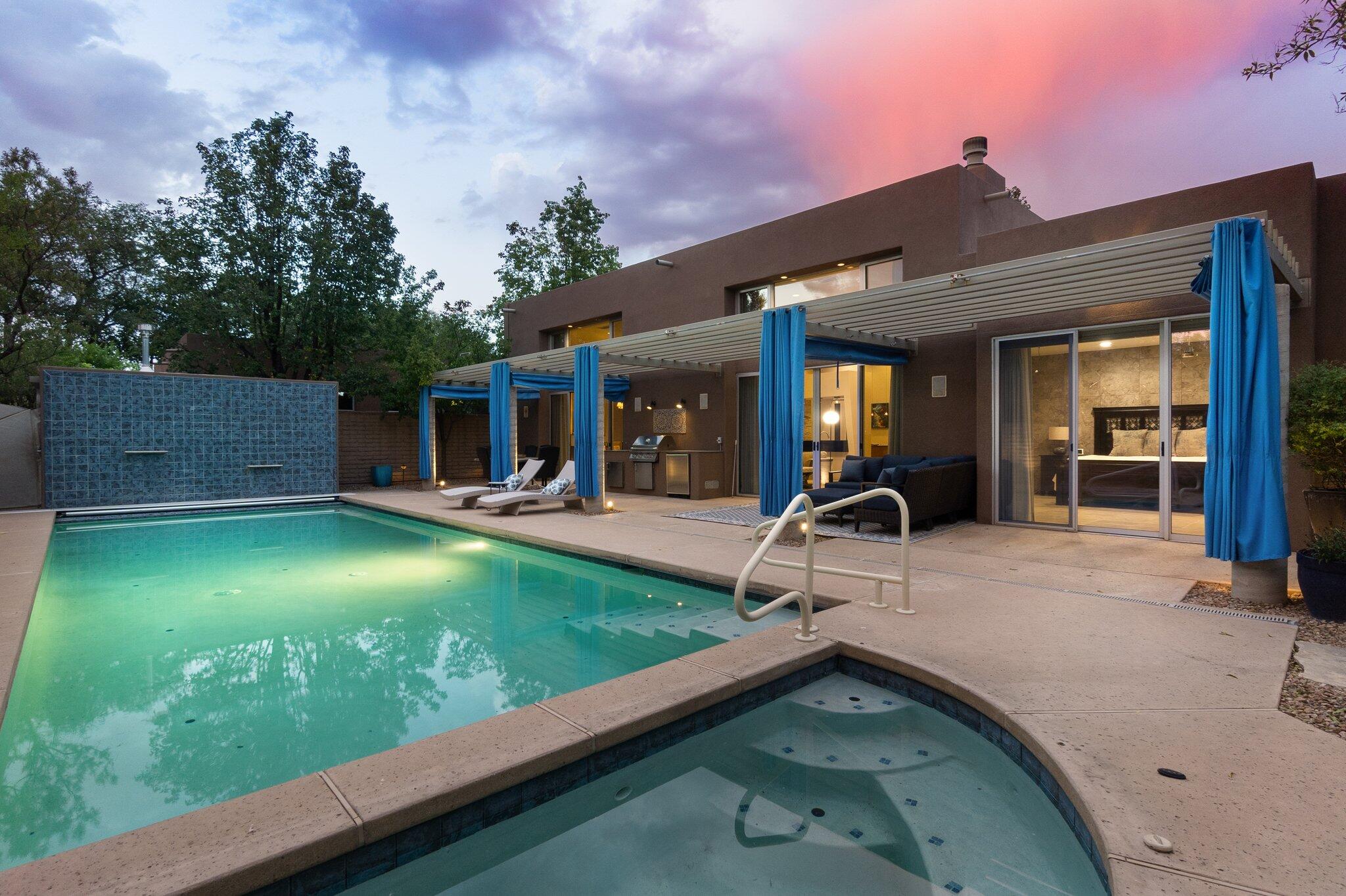 Custom, modern home in an exclusive, unique, verdant gated community Old Town  just a short walk or bike the Bosque & miles of trails leading to zoo, bio park, coffee shops and more. If you love the urban lifestyle with fine & casual dining, wineries, breweries, shops, museums, Sawmill & many other nearby attractions, these amenities are within a few blocks. As for this gorgeous property it is nestled amongst majestic cottonwoods and boasts incredible indoor & outdoor living, designed w/thoughtful architectural privacy & beautifully appointed contemporary flair, fine lines, high ceilings, gas fireplace, Italian porcelain tile & abundant natural light. Chef's kitchen has dual Wolf ovens, gas cooktop, Sub Zero fridge/freezer & large pantry. Owner's retreat complete with fireplace, luxurious