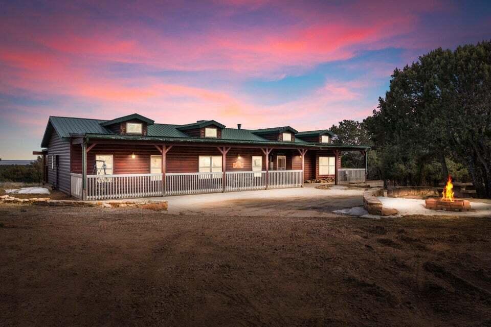 Escape to your own private sanctuary in Tijeras with this 4+ acre retreat, offering ultimate seclusion and peacefulness. Surrounded by the natural beauty of New Mexico's pine trees, this charming single-level ''log cabin style'' provides a picturesque setting for enjoying fresh air and stunning sunrises and sunsets from the comfort of your own covered front and back porches. Step inside to discover custom details throughout, including tongue and groove ceilings, vigas, and a striking stacked floor to ceiling stone wood burning fireplace, perfect for cozy nights in. Entertain family and friends in a sunken family room in the heart of the home and even more space in the formal dining room. The split floorplan allows for privacy, with the primary suite located on one side and two guest room