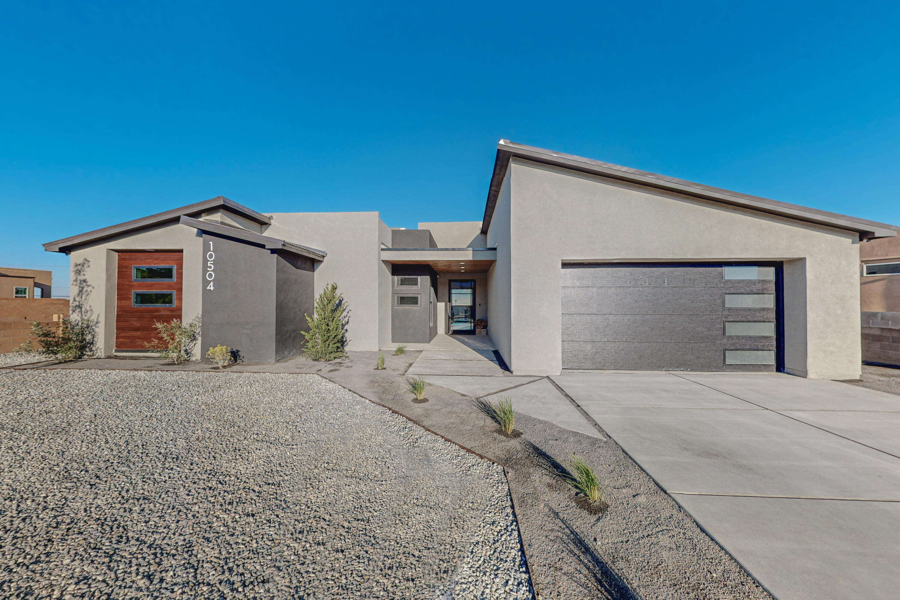 Welcome to 10504 Redbud Street NW, where modern interior elegance meets breathtaking exterior views of the Sandia mountains! This exquisite home was recently completed by Troyer Homes. It features Euro-style frameless cabinets, commercial-look Thor appliances, and large format tile, creating a harmonious blend of contemporary style and functionality. The oversized entry pivot door, tall 11' ceilings, custom fireplace and black Andersen windows enhance the ambiance and add a sense of spaciousness and luxury, while the rooftop deck, extra-large porch and built-in grill are perfect for entertaining guests.  Discover the epitome of luxurious living and unparalleled vistas! Schedule a showing today!