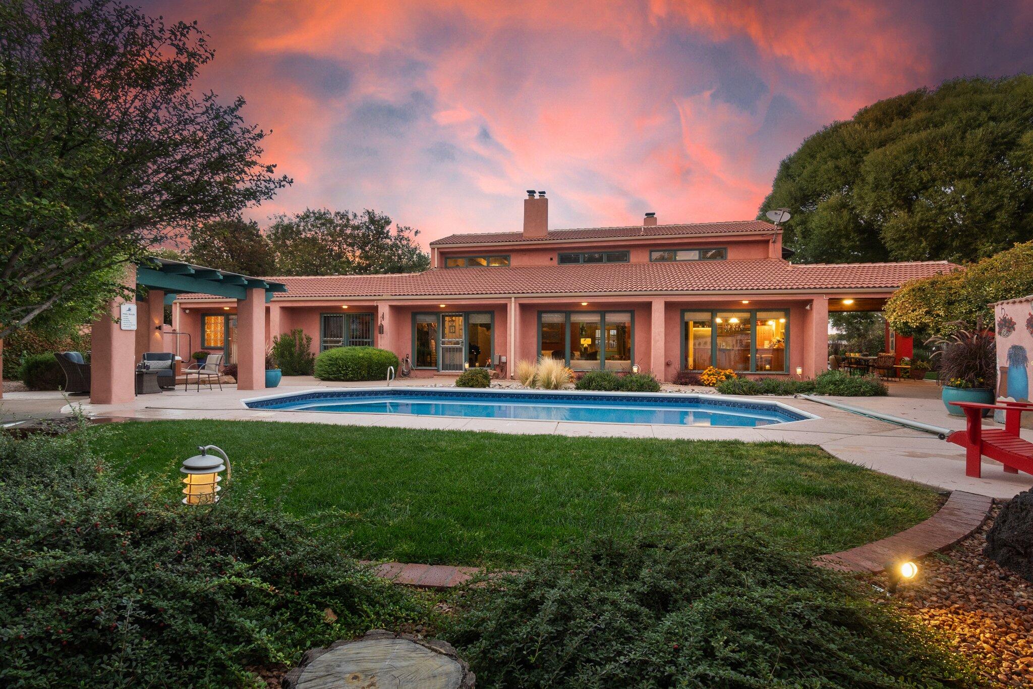 Nestled in the Valley's Green Belt, this exceptional property offers an abundance of amenities and a picturesque backdrop. Situated on a generous 1-acre lot are the primary residence plus a recreational building that features a domestic well, guest house, gym, workshop and a trailer garage. There are 3 additional spaces that once served as 2 horse stalls & a tack room which have been currently repurposed but could be reverted and just under 5 additional acres available to serve your horses/animals or simply to enjoy the beauty of the incredible setting backing the bosque trails and the Rio Grande. The captivating main house exudes a unique blend of rustic charm and modern elegance, offering an inviting and comfortable living space with a range of distinctive features. Boasting passive..